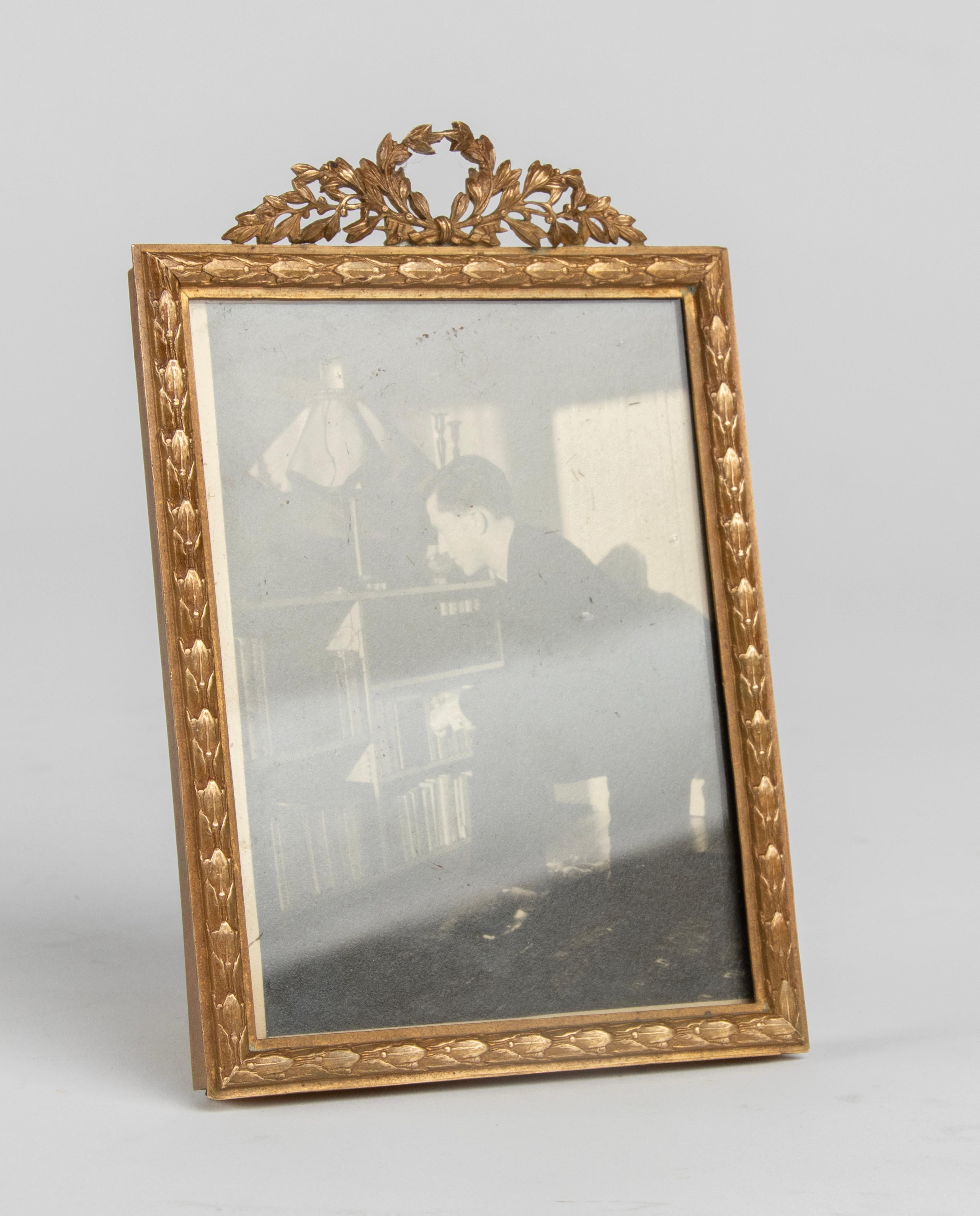 A refined antique photo frame, made of bronze, in Louis XVI style. On top a crest of laurel wreath. The trim is decorated with laurel leaves. Made in France circa 1880-1890. For on the wall or on a table.

Dimensions: 15 (h) x 10 x 7 cm 
Dimensions