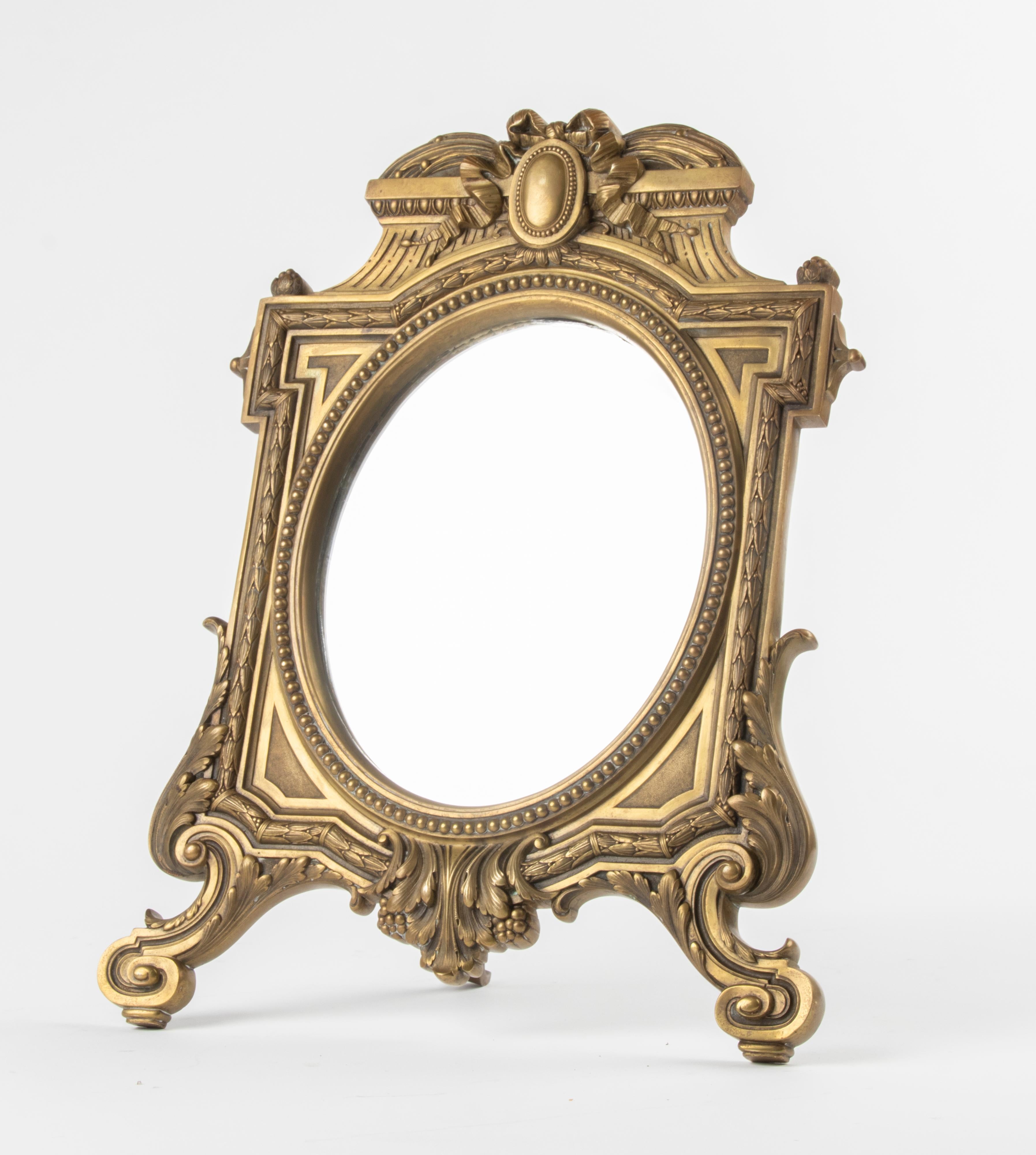 Antique bronze table mirror in Louis Seize style. The mirror is beautifully decorated with laurel leaf and pearl edges. The mirror dates from about 1880-1890 and comes from France. Nice old patina and in good condition.