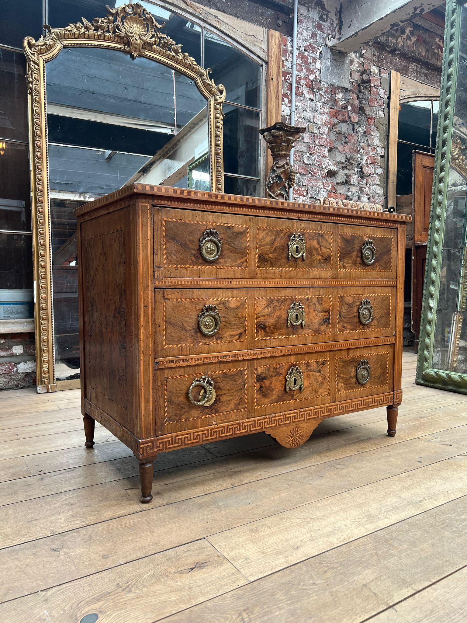Elégante commode de style Louis XVI présentant un étonnant placage de marqueterie et des incrustations raffinées. Le bois magnifiquement grainé présente des motifs géométriques et floraux complexes encadrés par des incrustations de bois clair et