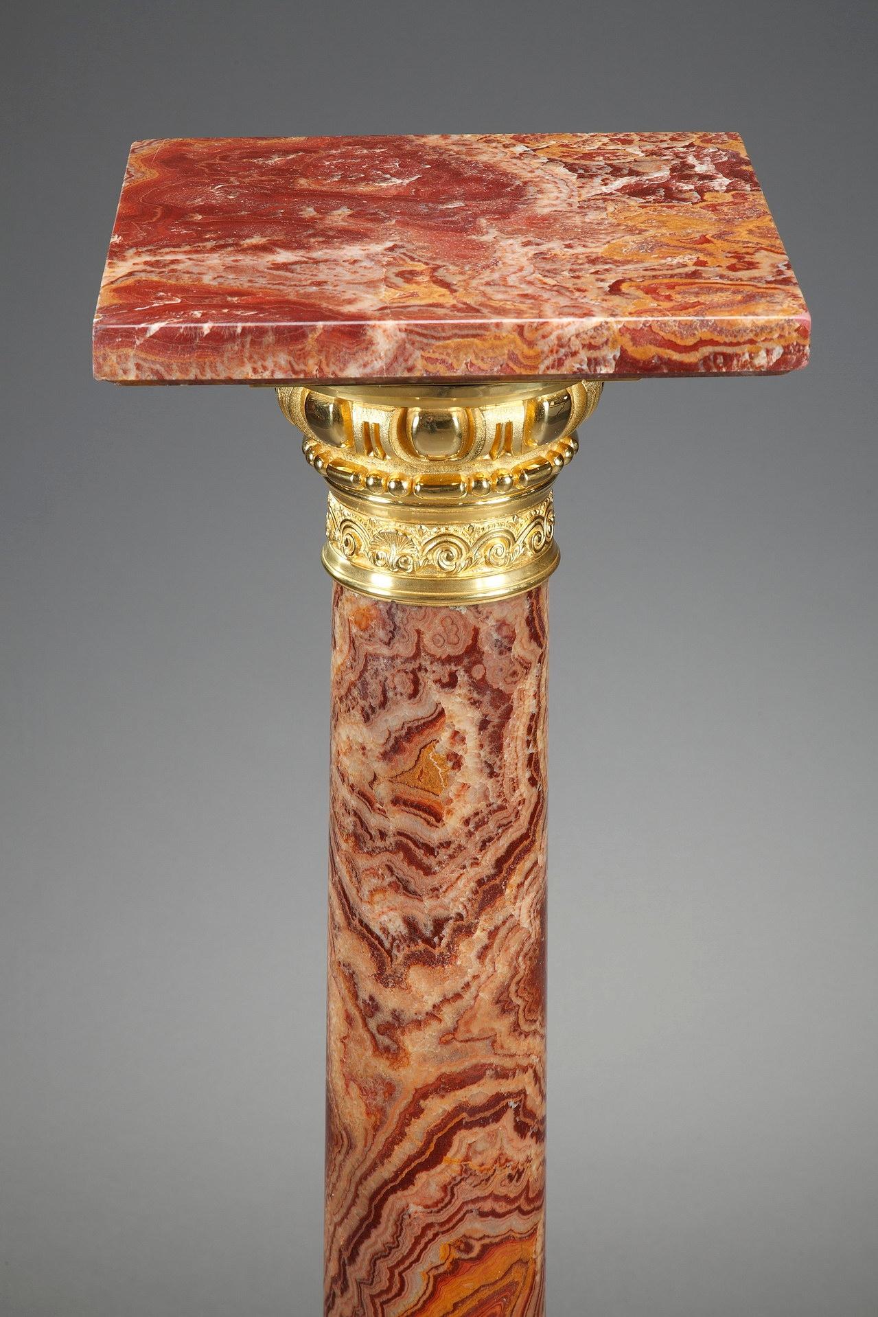 Louis XVI-style pedestal with a rotating display plate. Crafted in pink marble the late 19th century, this neoclassical column is highlighted with gilt bronze accents: ova, waves, shells and laurel crown. It is set upon a square, terraced base and