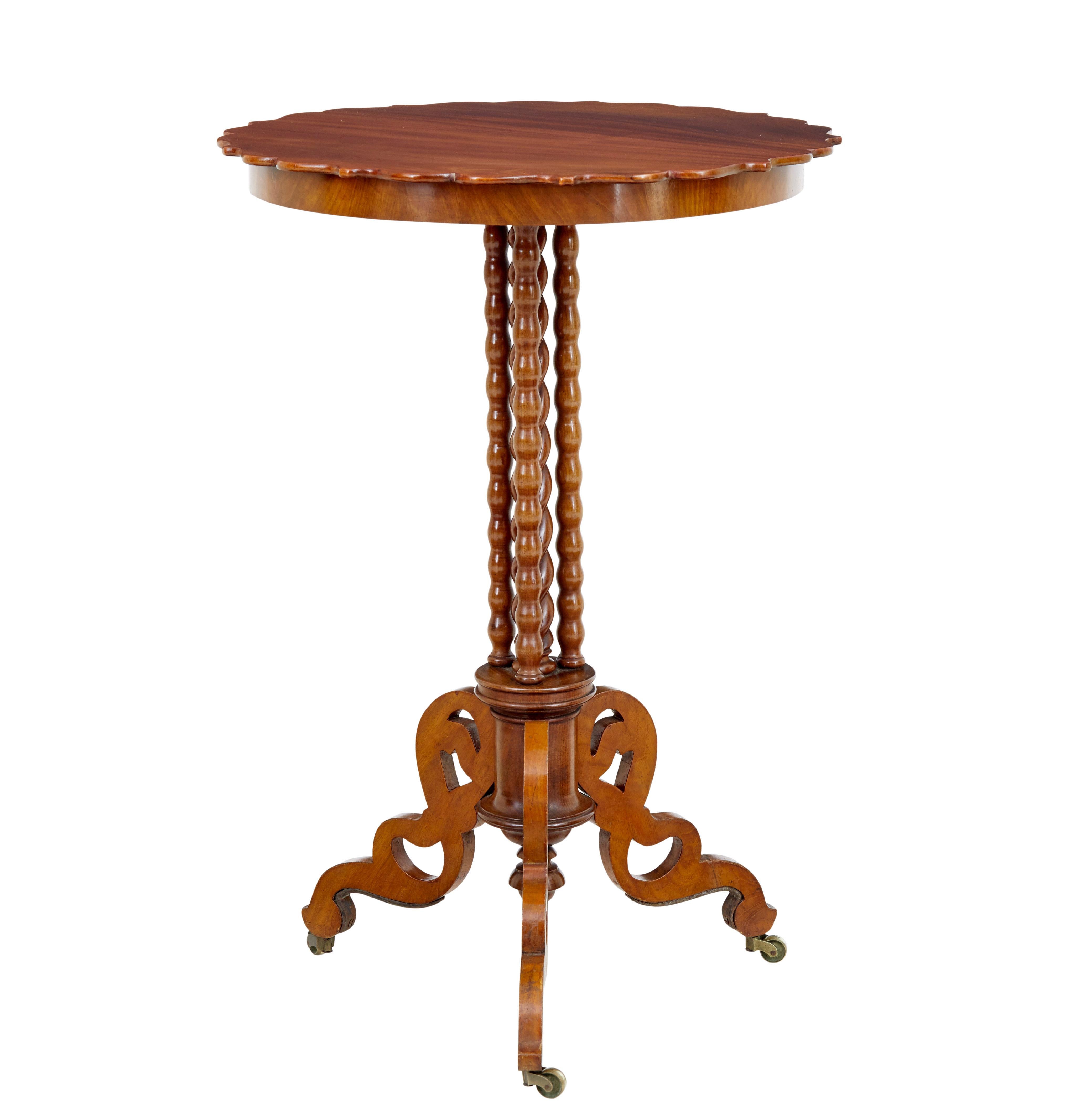 Late 19th century mahogany bobbin turned occasional table circa 1890.

Scalloped shaped circular top, which sits on a stem of 1 barley twist stem surrounded by a further 3 barley twist supports, all supported on 3 fret cut scrolling legs and brass