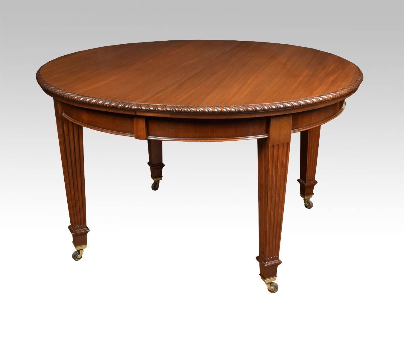 

Late 19th century mahogany dining table, the rectangular top with oval ends having gadroon carved edge to the telescopic action, with solid mahogany runners opening to incorporate three leaves all raised up on tapering and reeded legs with brass