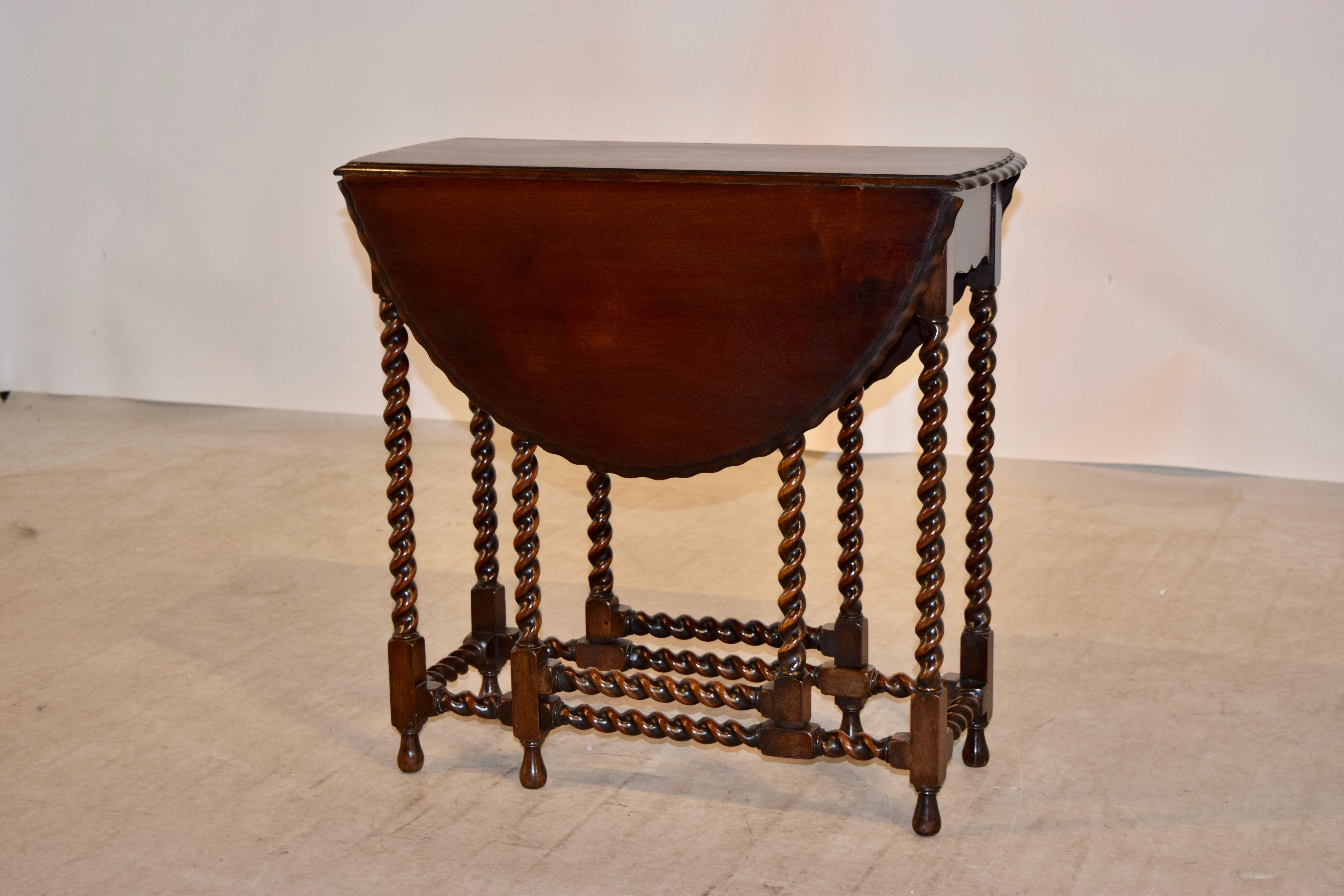 Late 19th century English gate leg table with a double scalloped and beveled edge, following down to a scalloped apron and supported on hand-turned barley twist legs, gates, and stretchers and resting on hand-turned feet. The top open measures 31.75