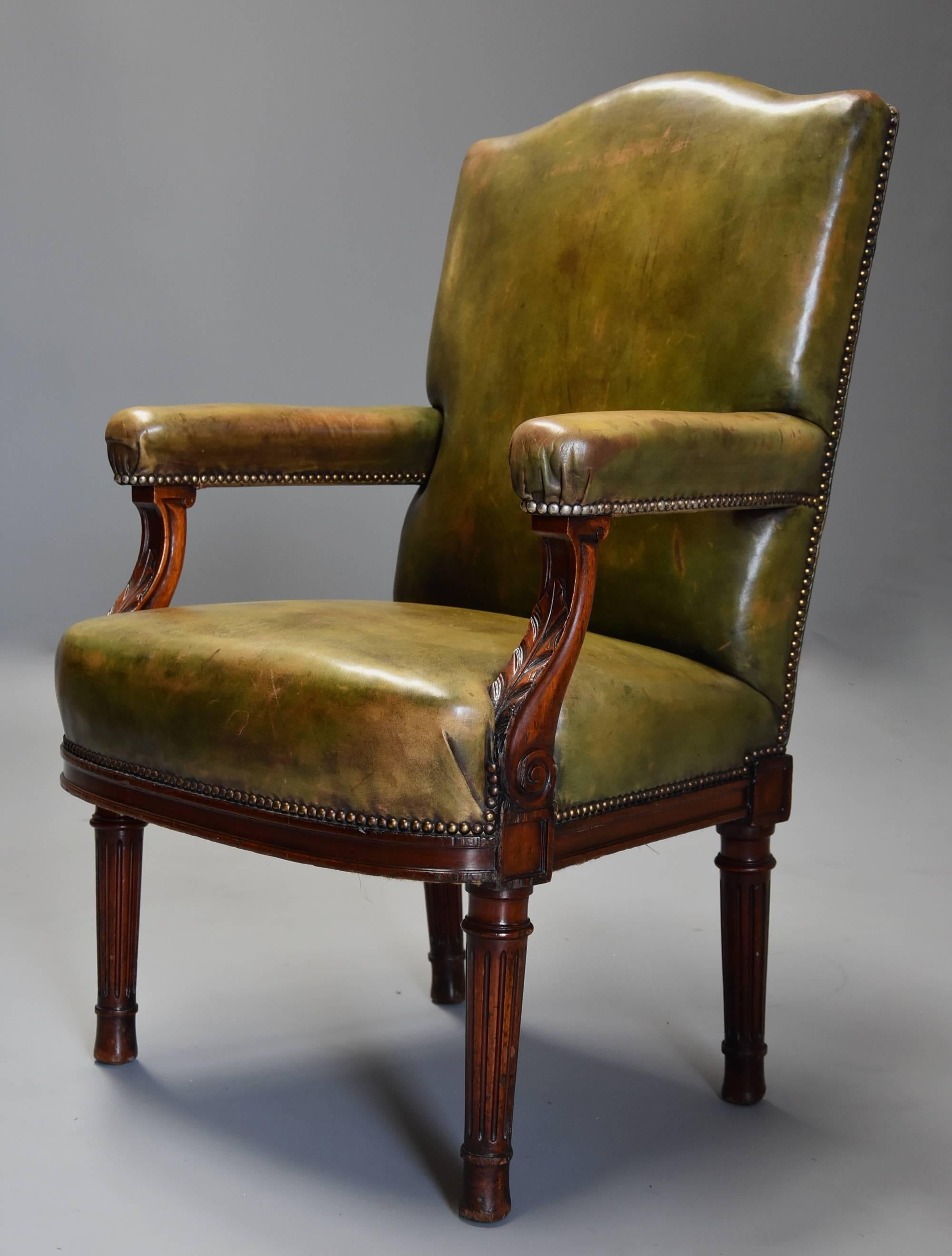 A late 19th century mahogany open armchair upholstered in a mottled green leather.

This chairs consists of a shaped top rail with an upholstered leather back, seat and arms, the arm supports being shaped and carved with leaf decoration.

This