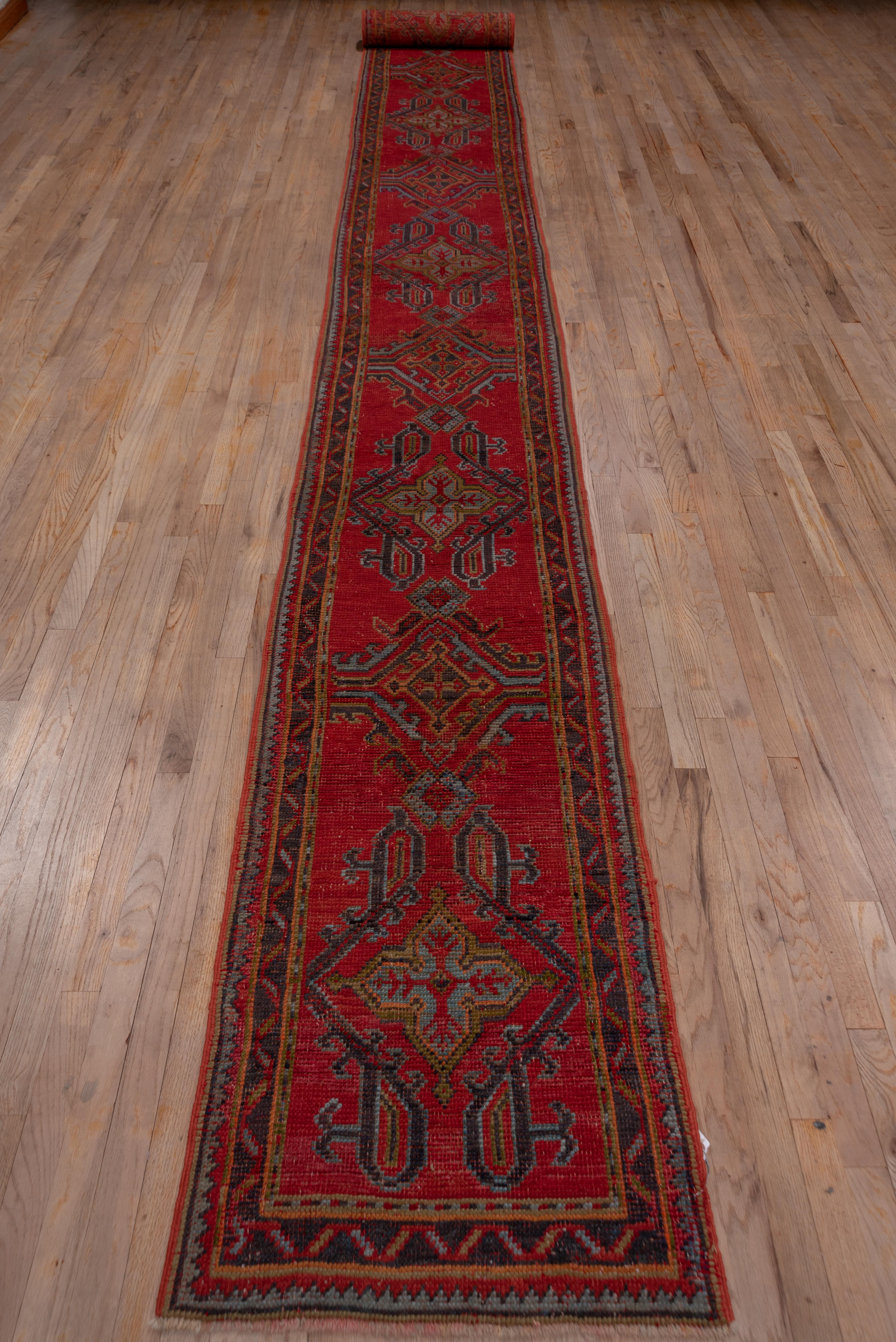 The Turkey red field of this western Anatolian town runner displays the Classic Yaprak (leaf) pattern in dark green, light blue and rusty orange while the forest green main border has a zig-zag motif.
