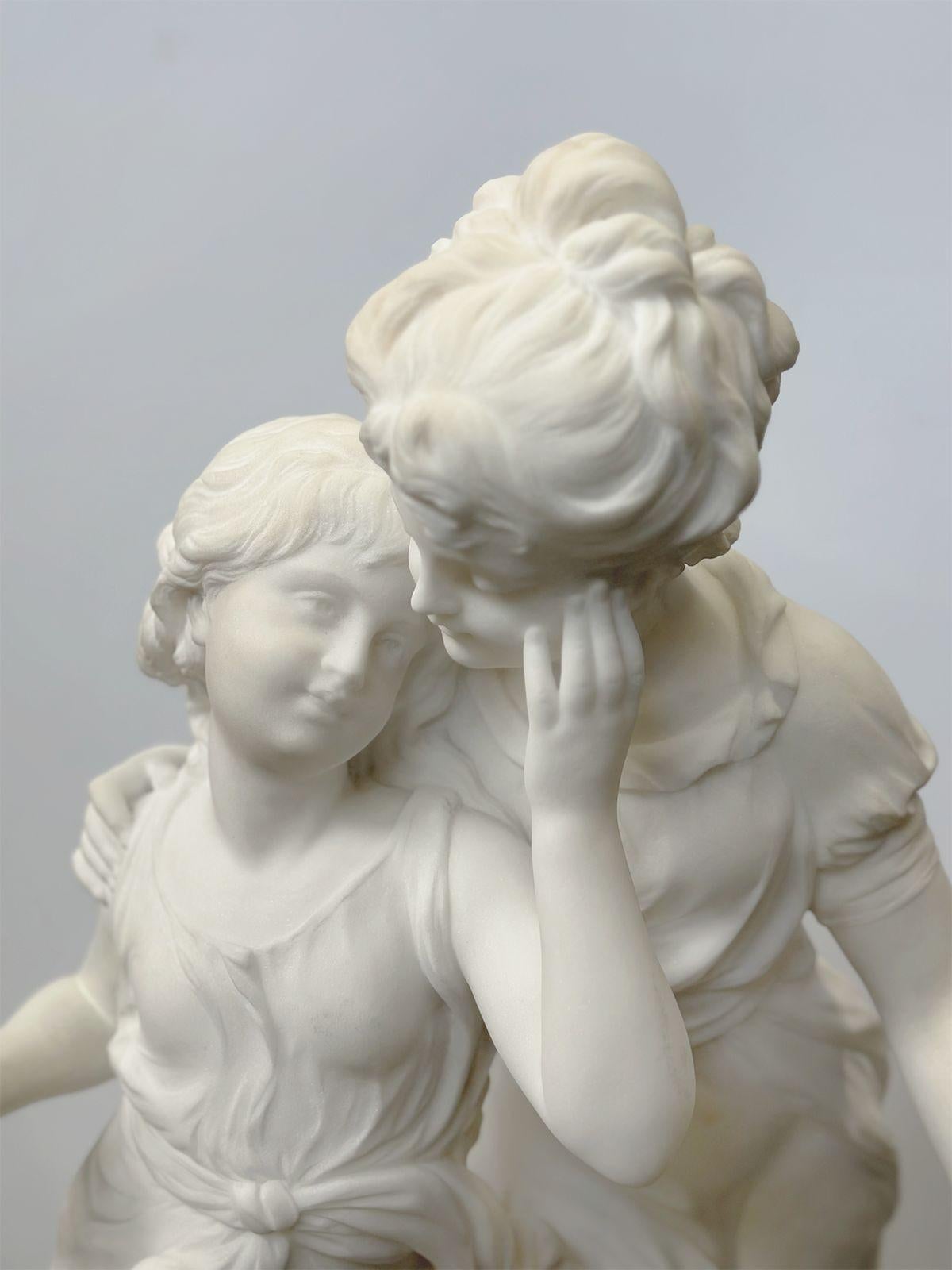 Sculpture en marbre français de la fin du XIXe siècle, sculptée à la main, représentant deux jeunes filles se tenant gracieusement ensemble et portant des vêtements traditionnels. L'une d'elles semble tenir une fleur. Signé sur la base 