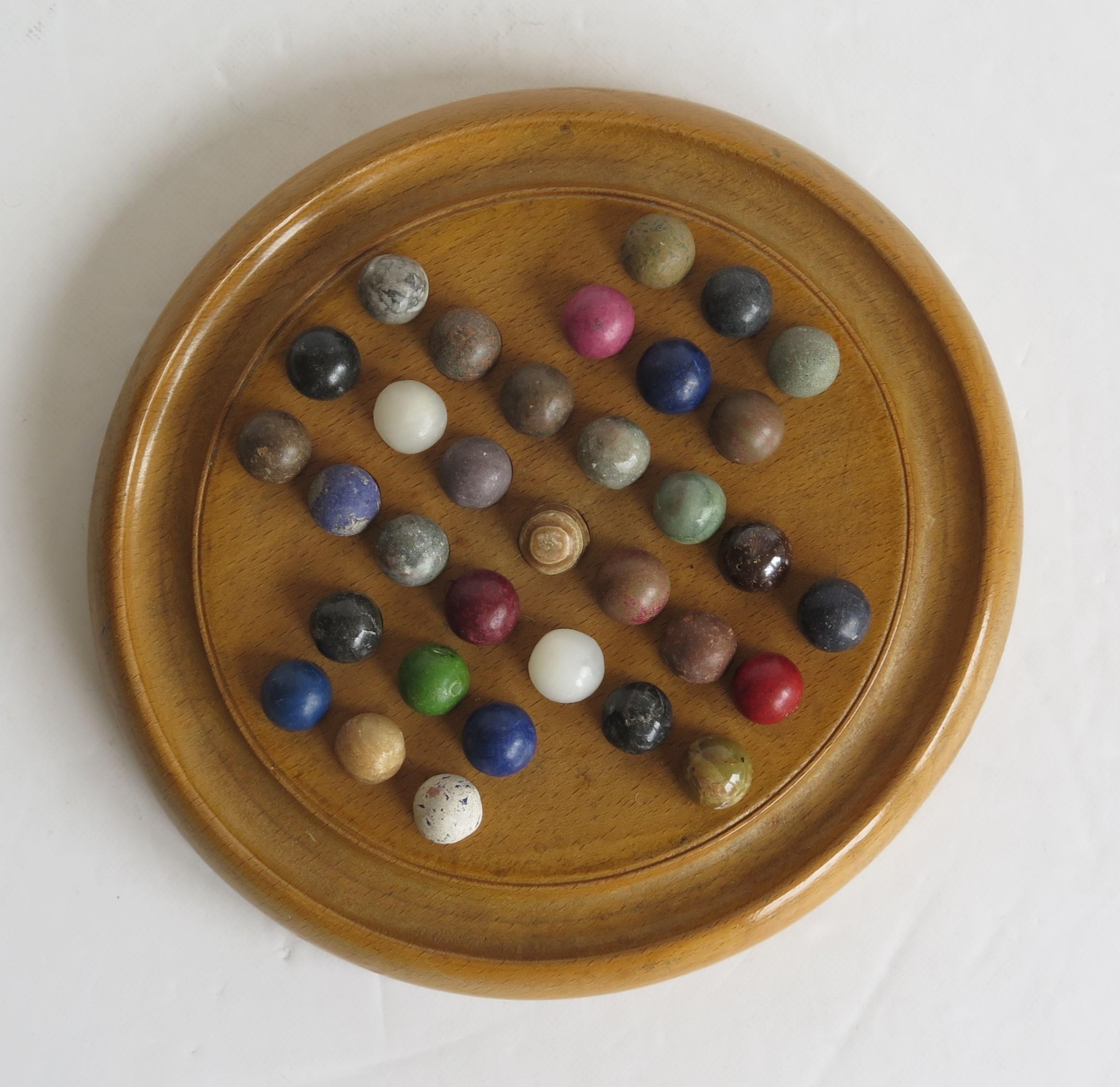 This is a complete game of marble solitaire from the late 19th century.

The circular turned board is made of a light coloured hardwood, probably Ash. The board has 32 equi-spaced holes with an additional one in the centre and a gallery to the
