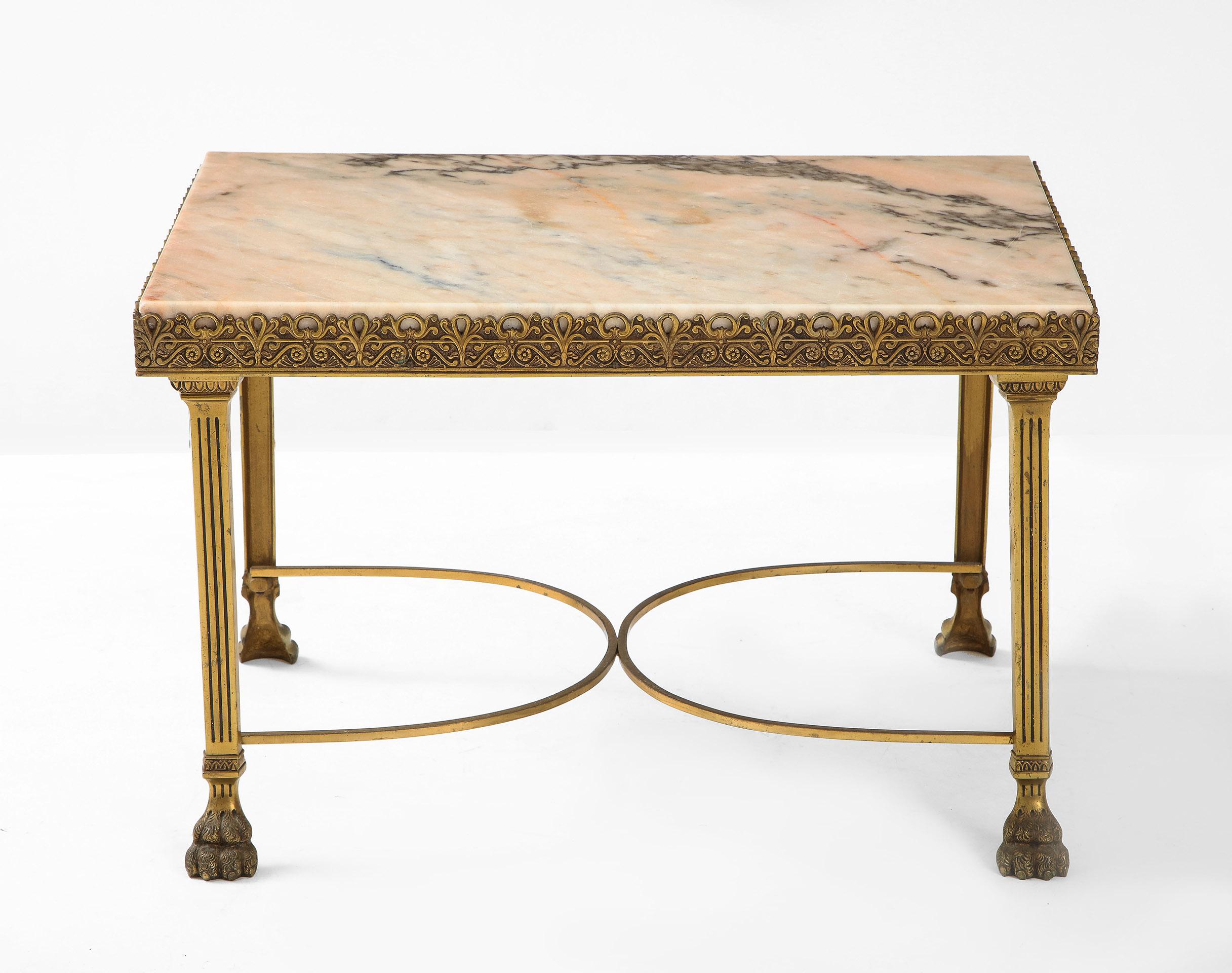 The inset marble top with an embossed brass filigree frame supported by fluted column legs with cross stretcher and ending in lion paw feet.