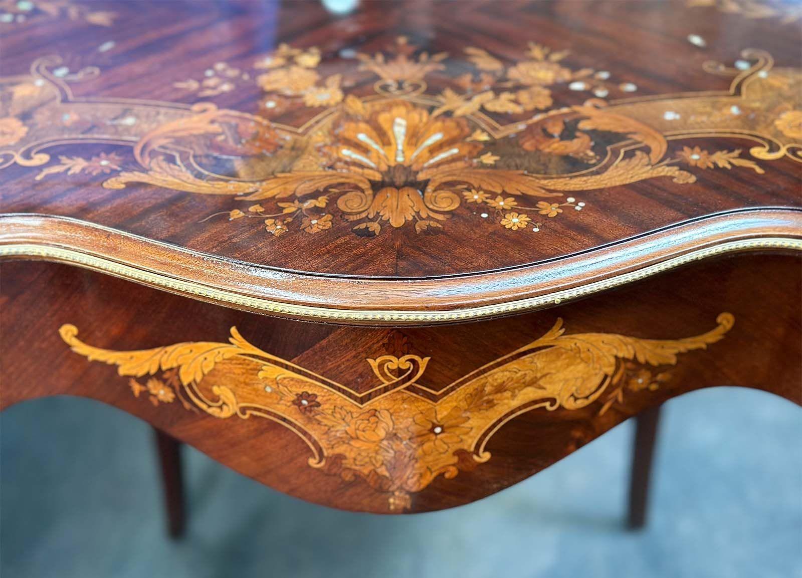 This exquisite French side table, crafted in the late 19th century, showcases the timeless beauty of wooden marquetry combined with elegant mother of pearl accents and intricate bronze mounts. The table's stunning marquetry work features intricate