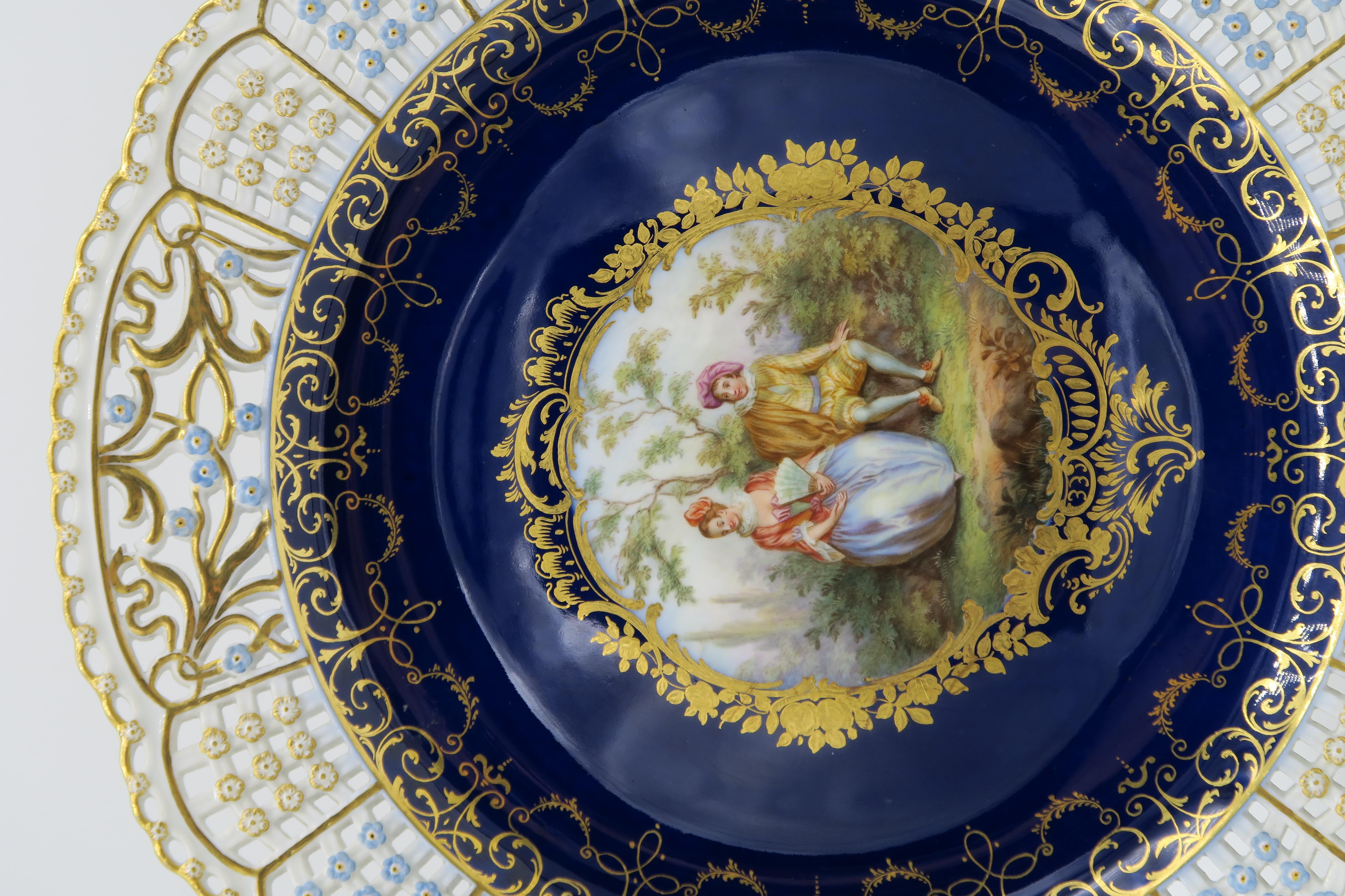 German Meissen Porcelain reticulated plate. Depicting classical romantic scenes, signed with blue crossed swords.

Meissen Prunk-Teller
Feine „Watteauszene“, und aufwendige Goldbordürenmalerei.
Fahne mit durchbrochenen Gitterfeldern mit