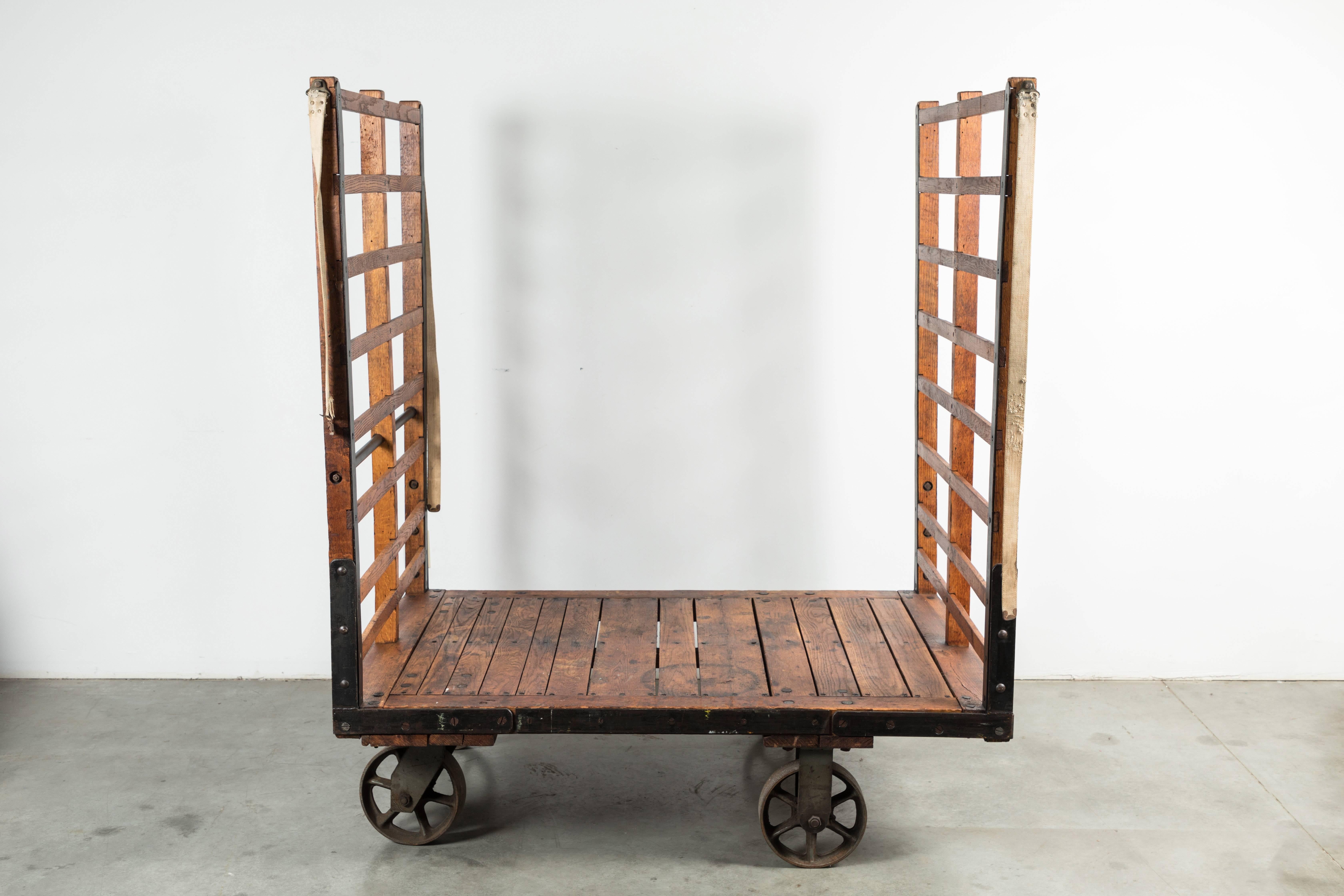 Late 19th century substantial luggage cart from a Midwestern United States train station. Cart moves on four cast iron casters. Wood slats with riveted and woven fabric straps. Stencilled with cart number and station info. Found at Union Station in