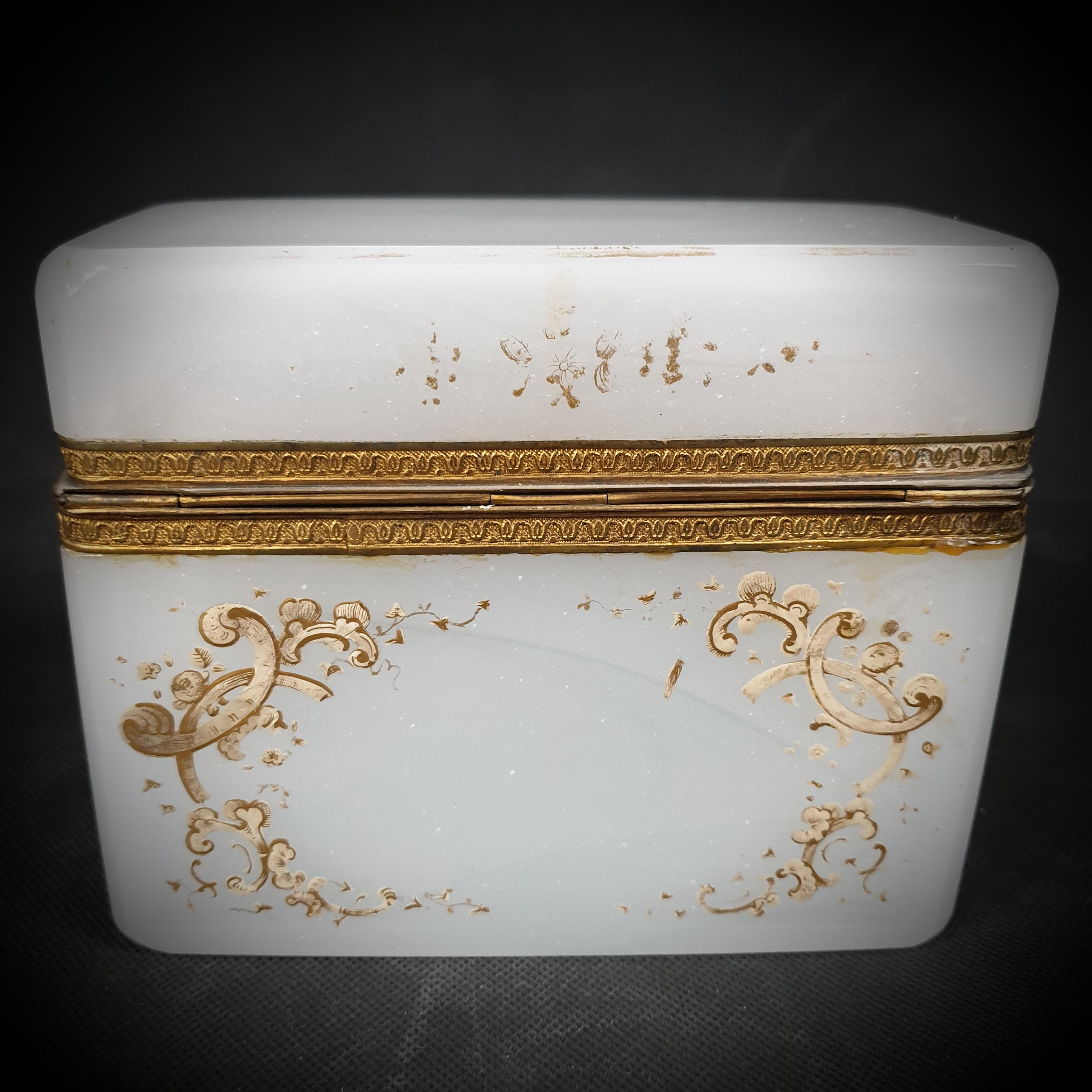 This antique Bohemian opaline glass box is a work of art that has withstood the test of time. Because of the beautiful gold gilding that covers all four sides, this exquisite piece of milky white glass is a treasure for collectors and art lovers.