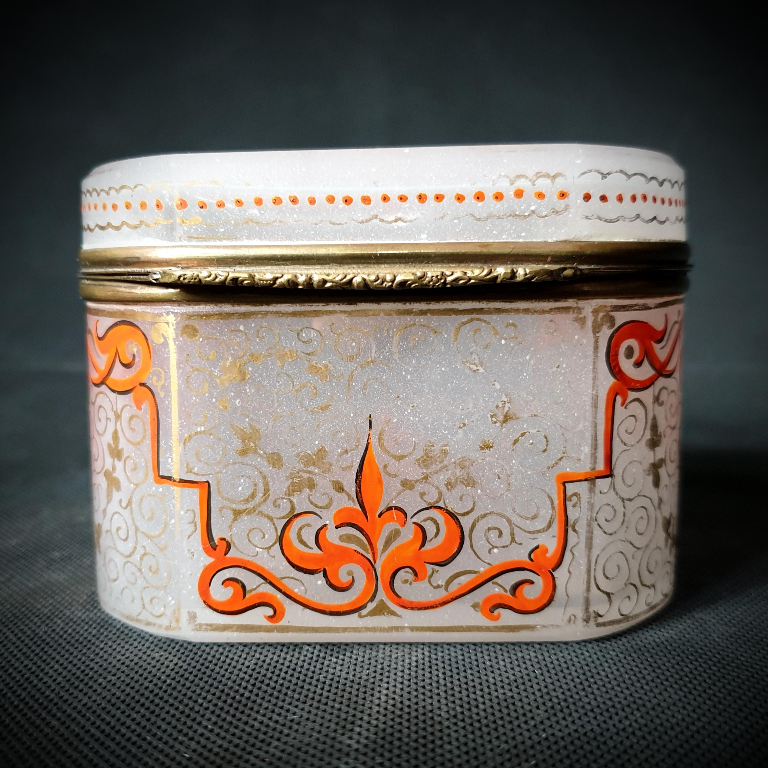 Diese schöne Dose aus Opalglas und Kupfer wurde zwischen 1850 und 1900 von französischen Handwerkern hergestellt. Die orange-roten Moser Blumenmuster auf dem weißen Milchglas sind wunderschön und raffiniert und verleihen jedem Raum einen Hauch von