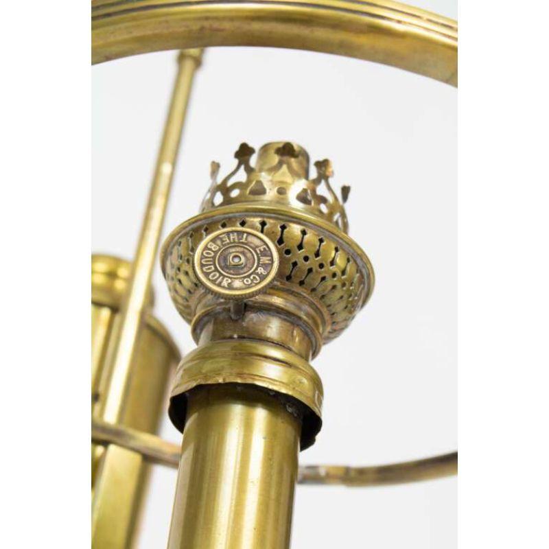 Brass oil lamp with adjustable arm. Shade ring is attached to the arm. Made in the US around 1880. Marked “E.M & Co. THE BOUDOIR” on the Burner knob. Simple brass construction with a simple ring at the top. Brass has been cleaned, with light patina.
