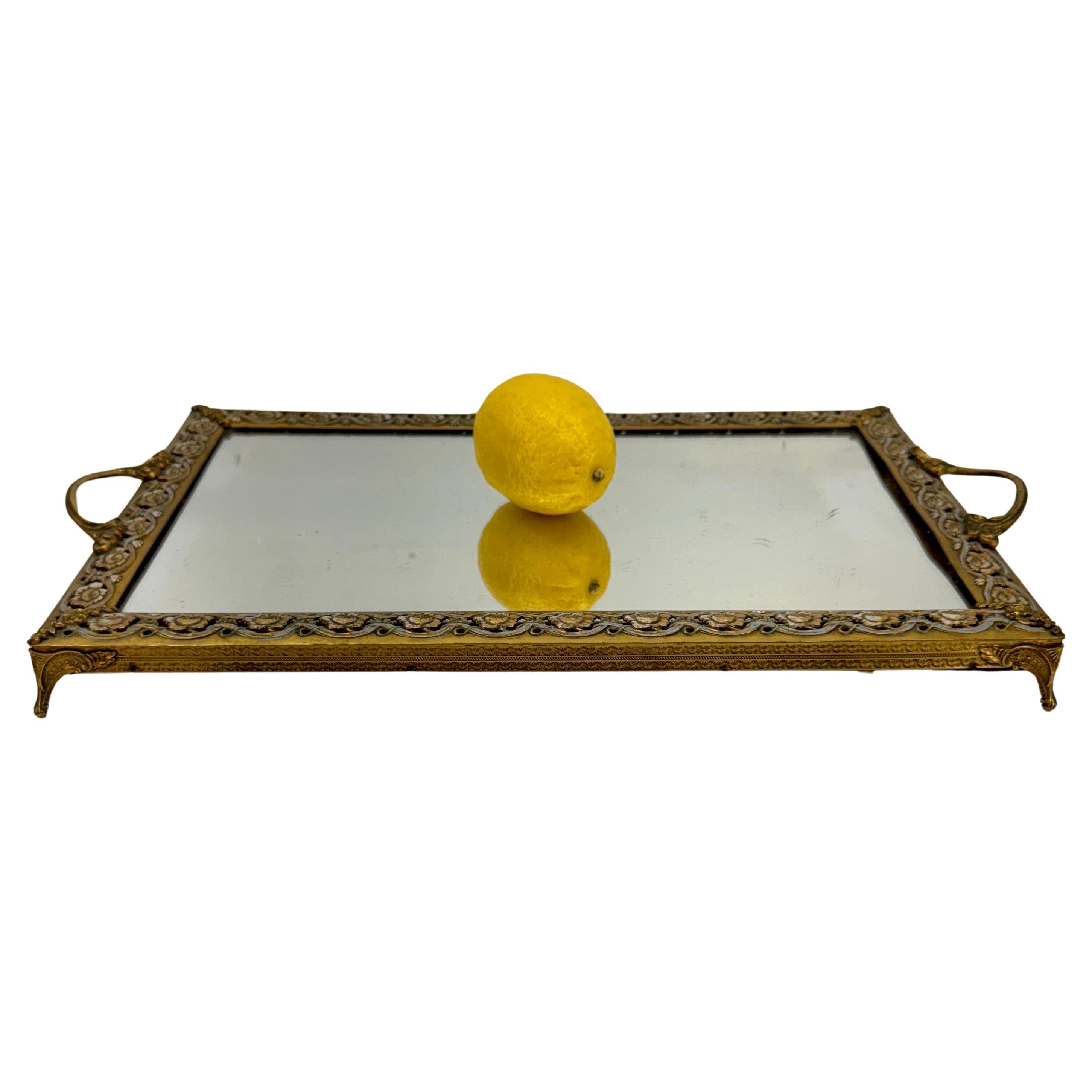 French Mirrored Brass Jewelry Tray, Late 19th Century

Charming French tray featuring an elaborate floral motif.. The attention to detail is apparent on this piece. The mirrored glass rests on the sturdy base. This tray with aged patina is perfect