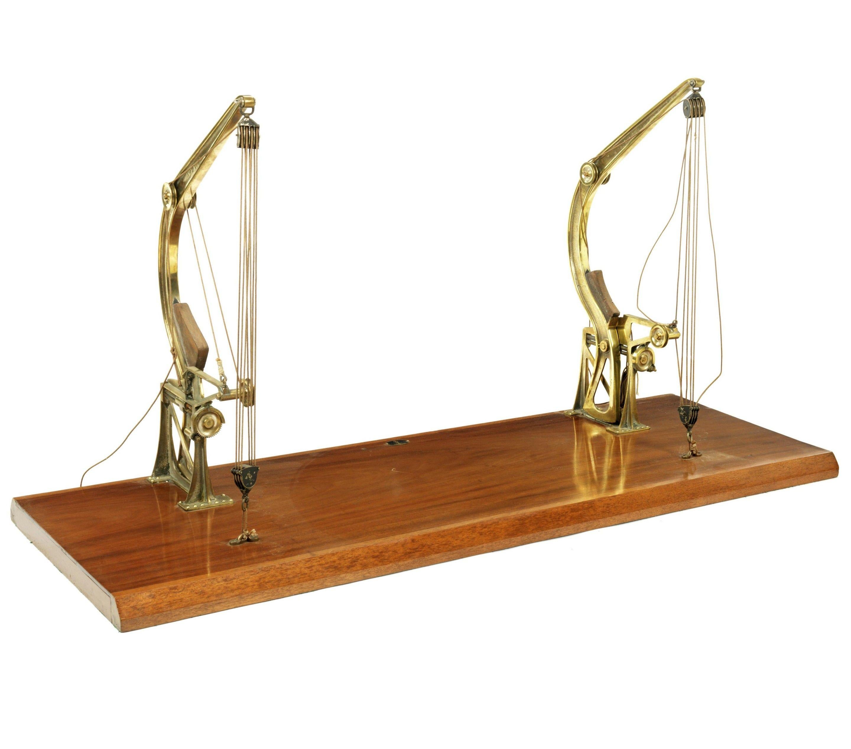 A late 19th century model of a pair of brass Davit type cranes 
each with corded mechanism, mounted onto a mahogany plinth base, with applied oval brass crown and anchor Admiralty plate.