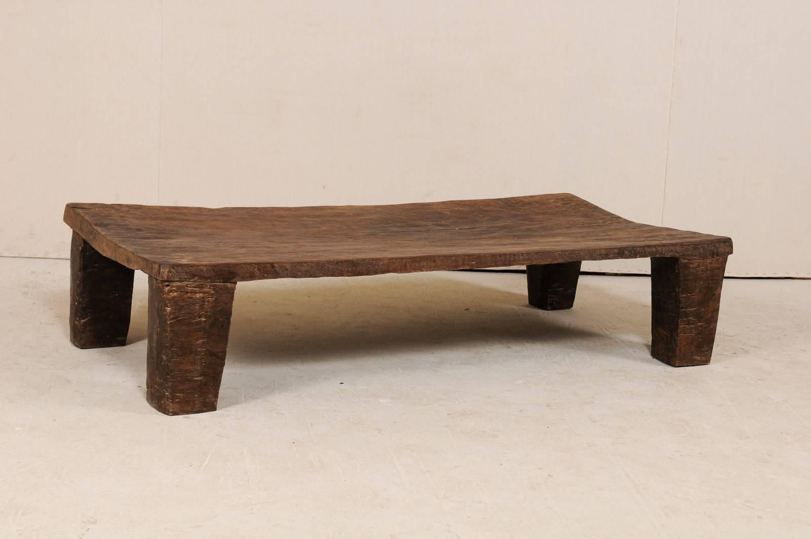 A primitive wood Naga coffee table from the late 19th-early 20th century. This turn of the century coffee table was originally used as a wooden bed from the Naga tribes of Nagaland, North East India. This piece has been carved out of a single log