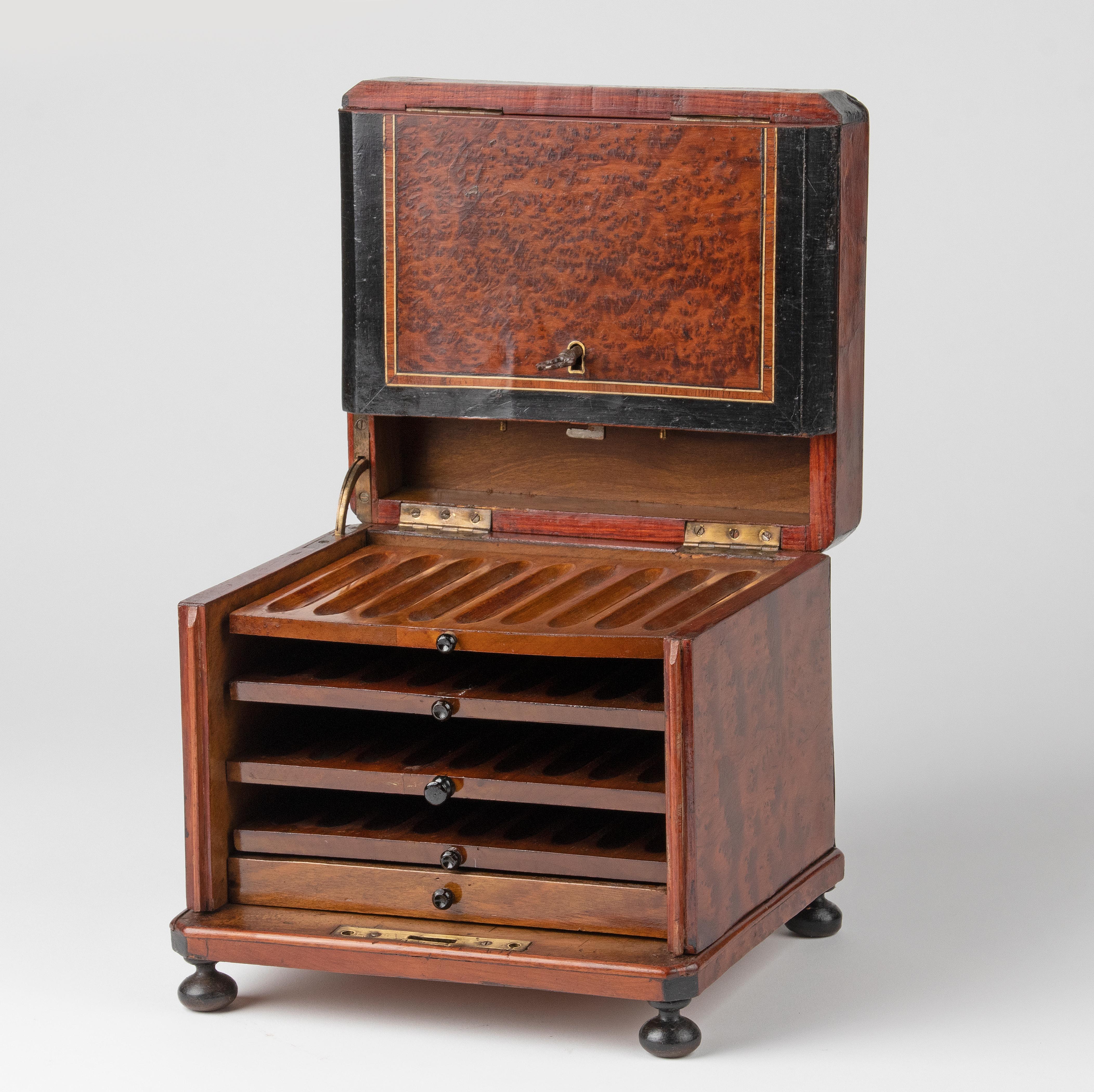 Antique cigar chest with room for 36 cigars. The chest is veneered with various kinds of wood, mostly burl walnut. On top a brass inlay. The interior has four drawers for cigars, made of mahogany, and 1 extra drawer for accessories. With working
