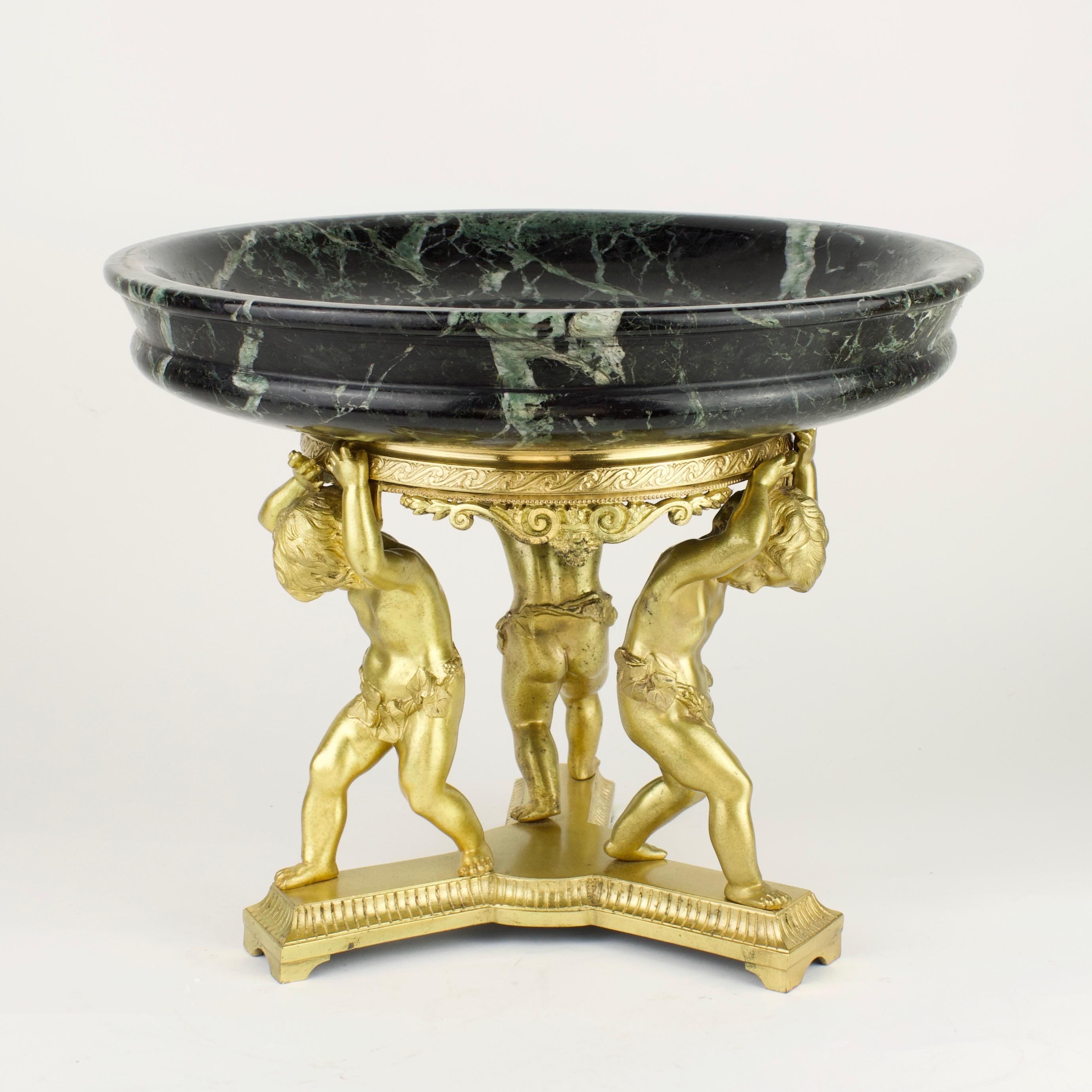 Late 19th Century French Empire gilt bronze putti and marble centerpiece

The centerpiece stands on a triangular, fluted base with arched feet; on the triangular base three finely chiseled putti with open eyes draped in oak leaves who are