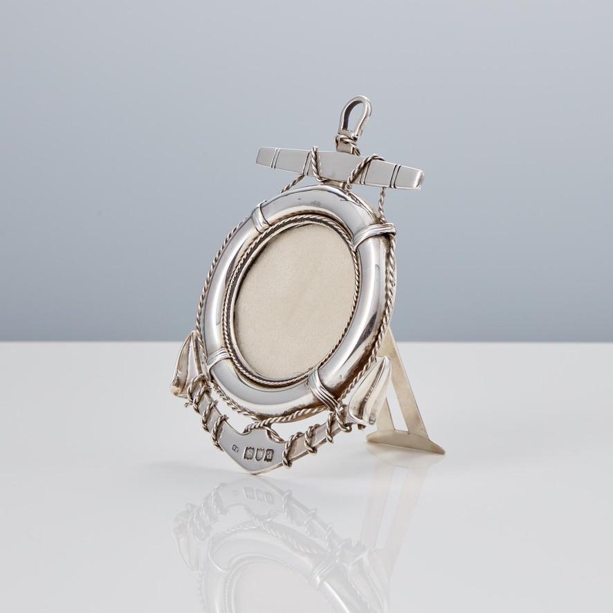 This cast silver anchor and lifebuoy photo frame is in excellent condition. 

The silver rope is beautifully entwined around the frame which enhances the intricacy of the piece. 

Maker; George Heath, London 1896. 

Dimensions:
H 4 1/4