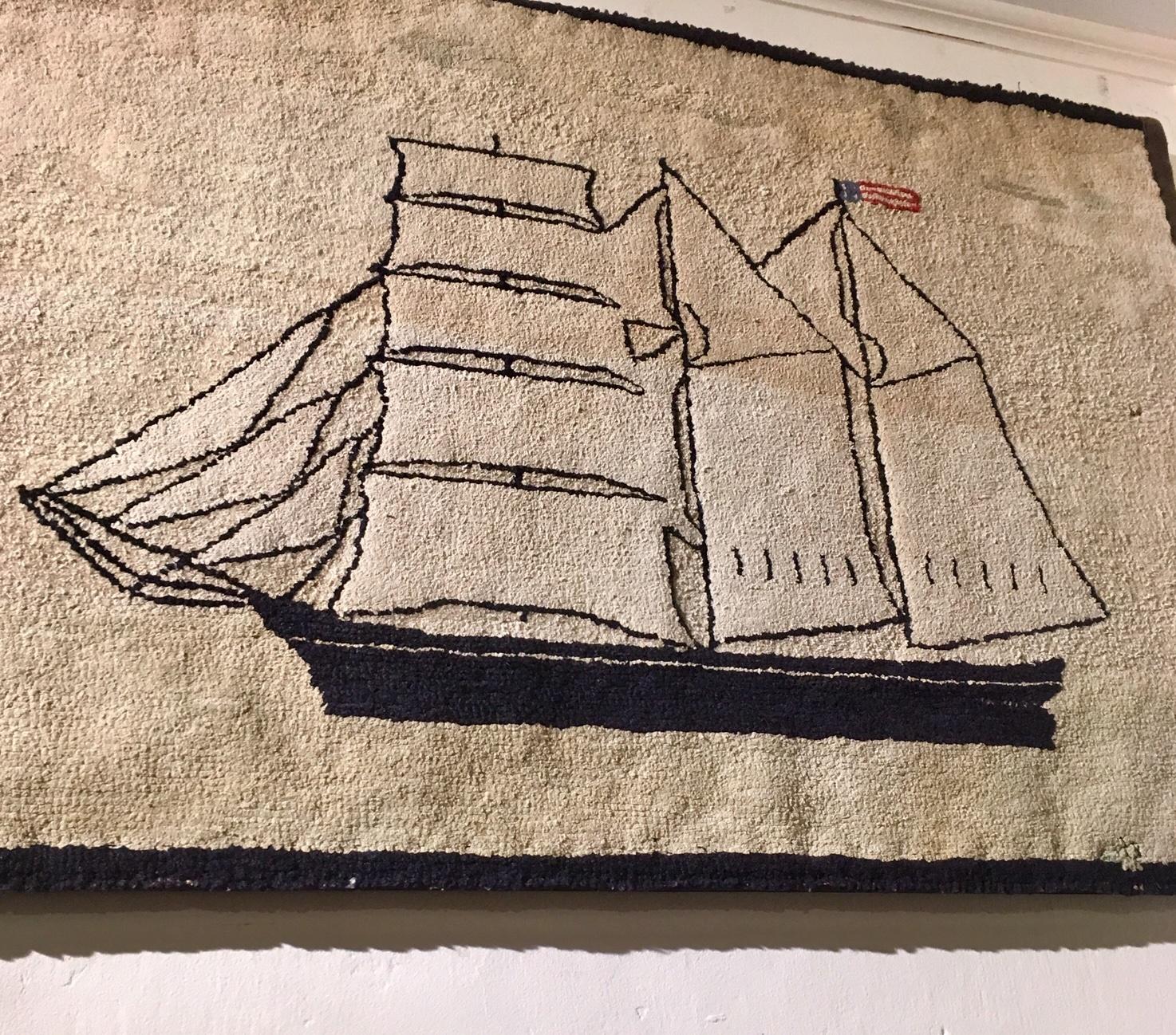 Late 19th century New England ship and lighthouse hooked rug, circa 1890. A hand hooked Folk Art hooked rug with naive image of a Barkentine under full sail, flying an American flag, approaching a lighthouse. In very good condition for its age,