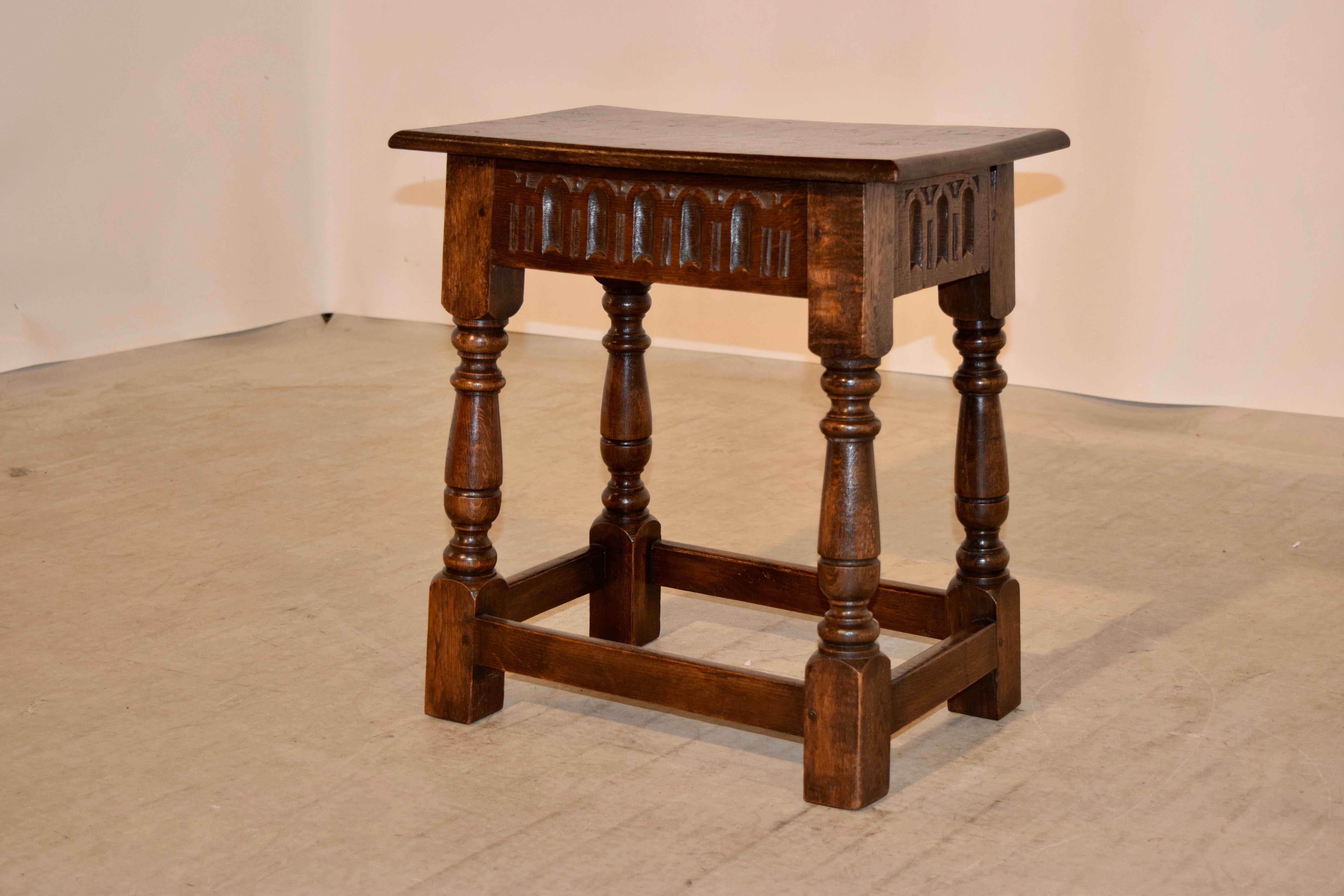 Late 19th century English oak joint stool with a beveled edge around the top following down to a hand fluted apron which is on all four sides and supported on hand turned splayed legs joined by stretchers.