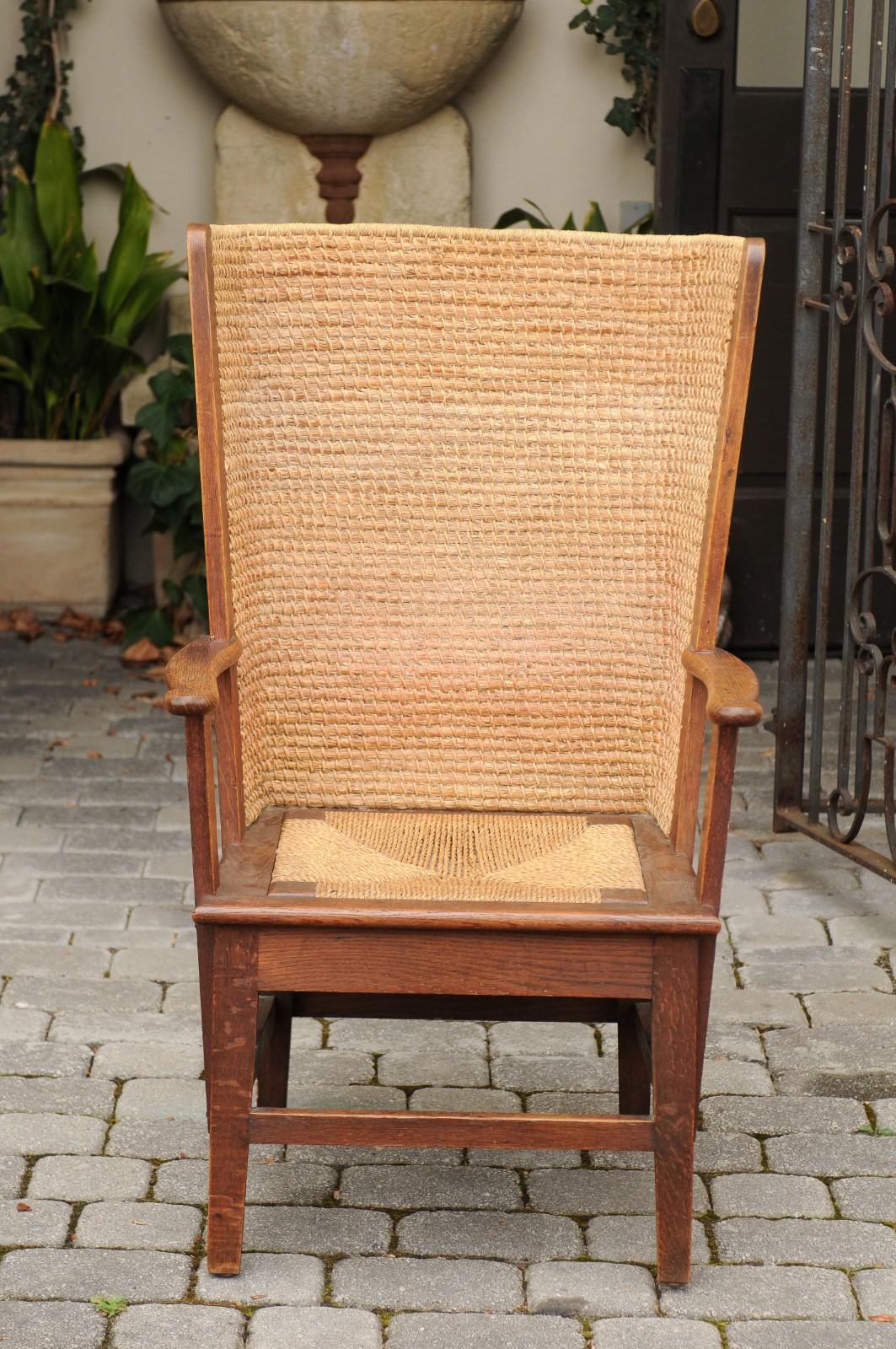 A Scottish Orkney Island oak wingback chair from the late 19th century, with handwoven straw back, rush seat, open arms, straight legs and side stretchers. Born in the archipelago of Orkney off of the northern coast of Scotland, this chair features