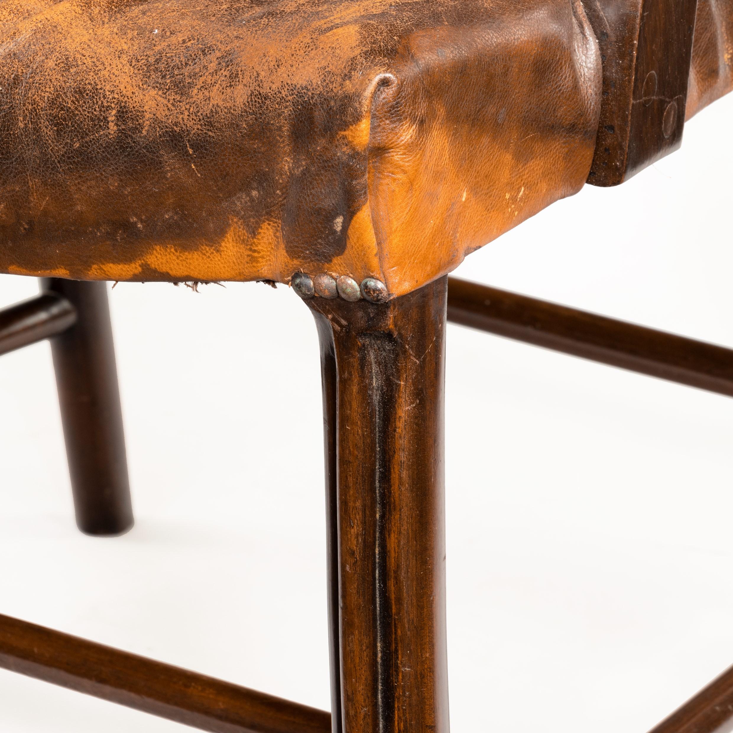 The old leathered seat raised upon slightly out swept legs.
English, circa 1890.