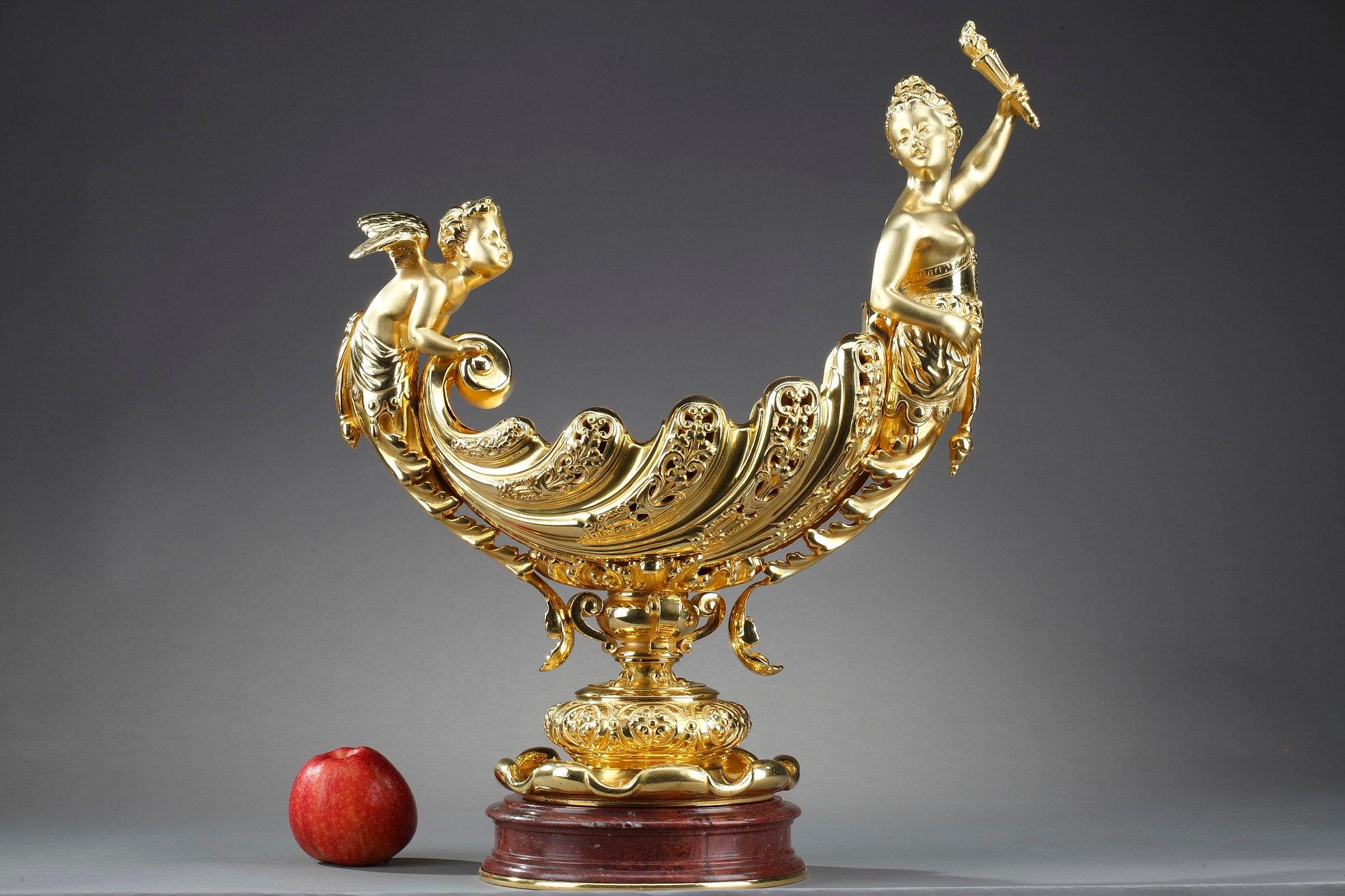 Gilt bronze or ormolu cup featuring Cupid and Aurora holding a torch. In Roman mythology, Aurora is the goddess of dawn and sister of the Sun. Every morning, she flies across the sky, announcing the arrival of the Sun. The cup symbolizes the chariot