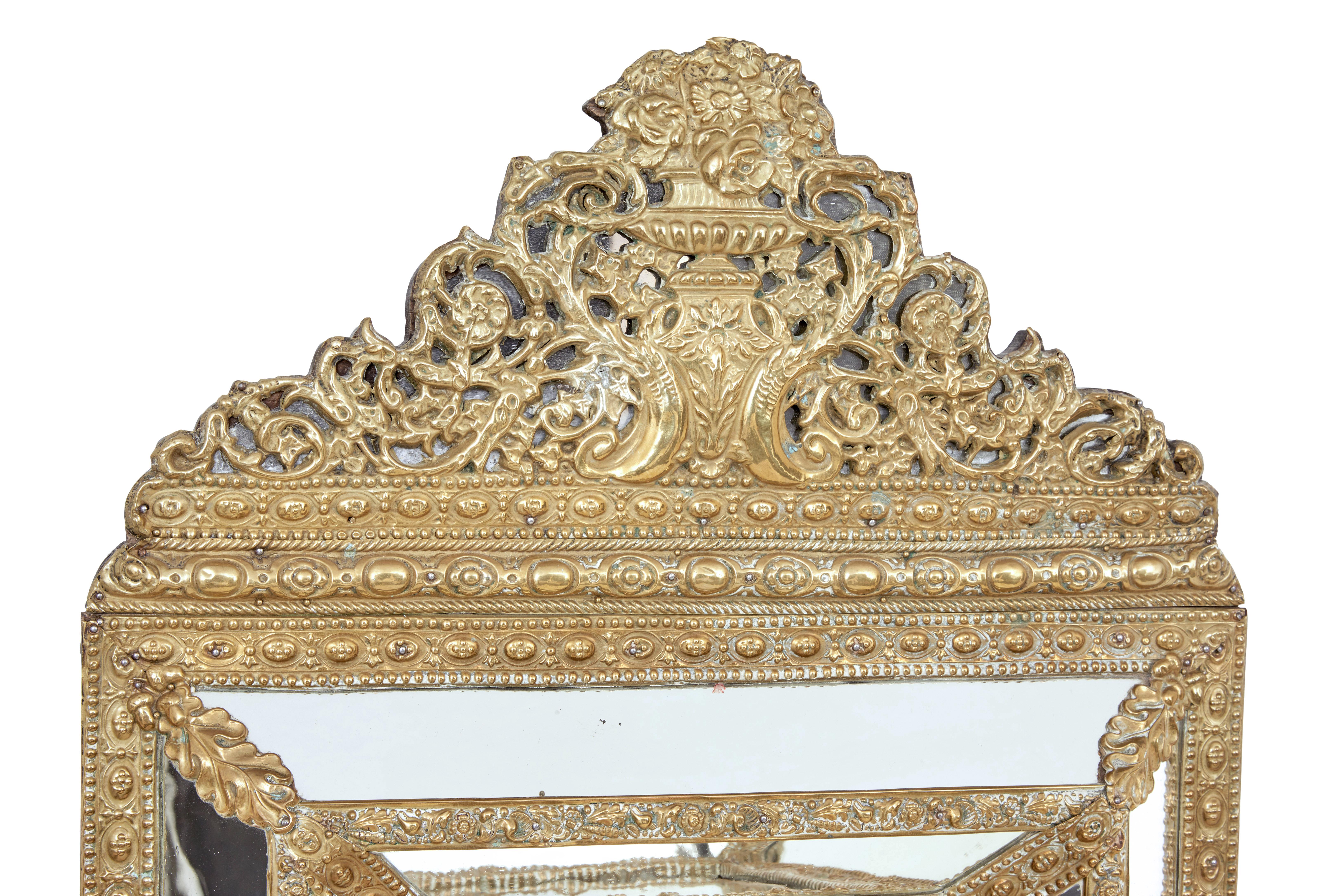 Late 19th century ornate brass cushion mirror, circa 1890.

Ornate pressed brass cushion mirror. Portrait orientation with decoration cornice of an urn and coat of arms.

Minor surface marks to metalwork, minor wear to mirror plate.
