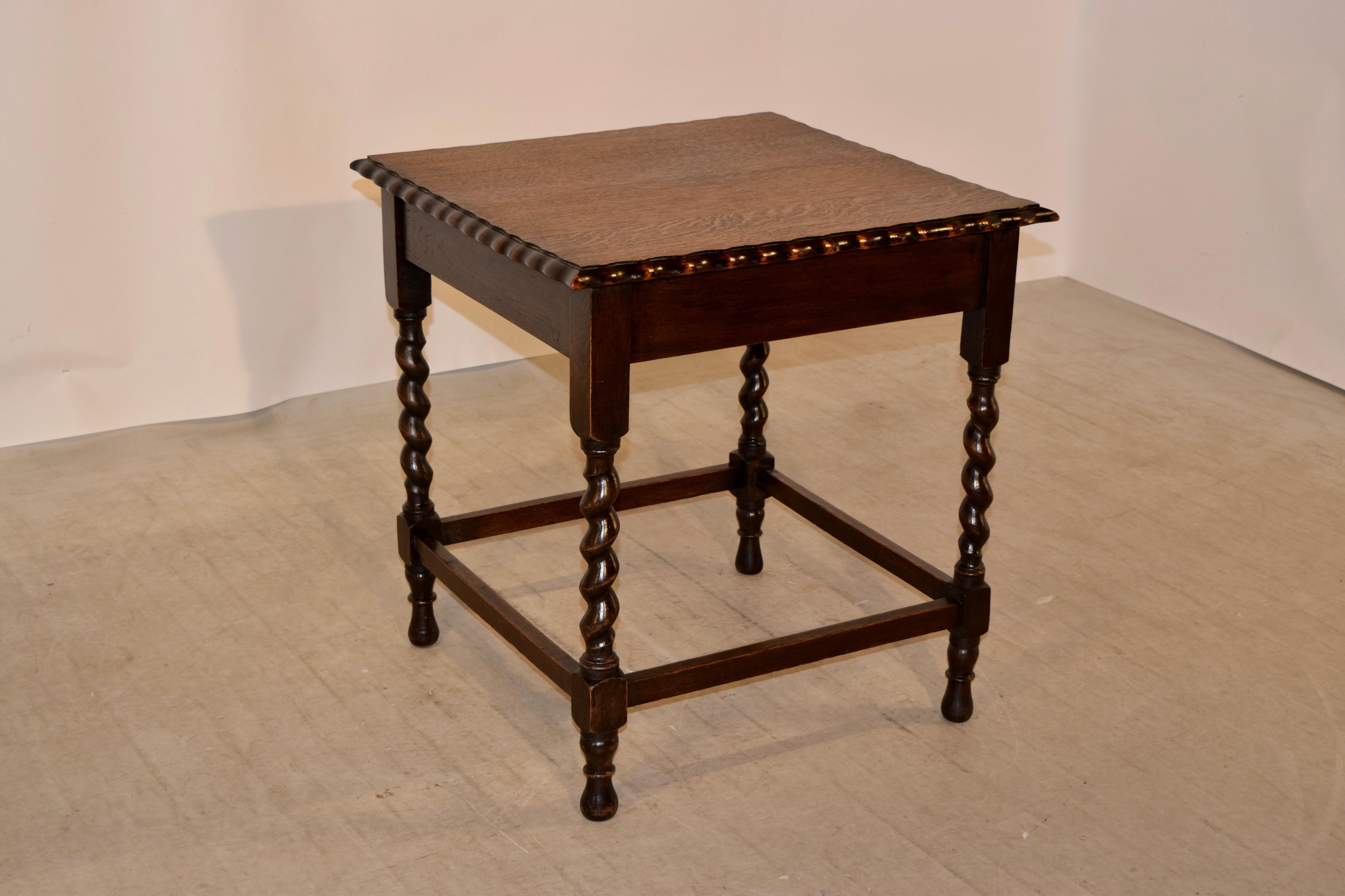 19th century oversized oak occasional table from England. The top has a scalloped and bevelled edge following down to a simple apron and supported on hand-turned barley twist legs joined by stretchers and raised on hand-turned feet.
