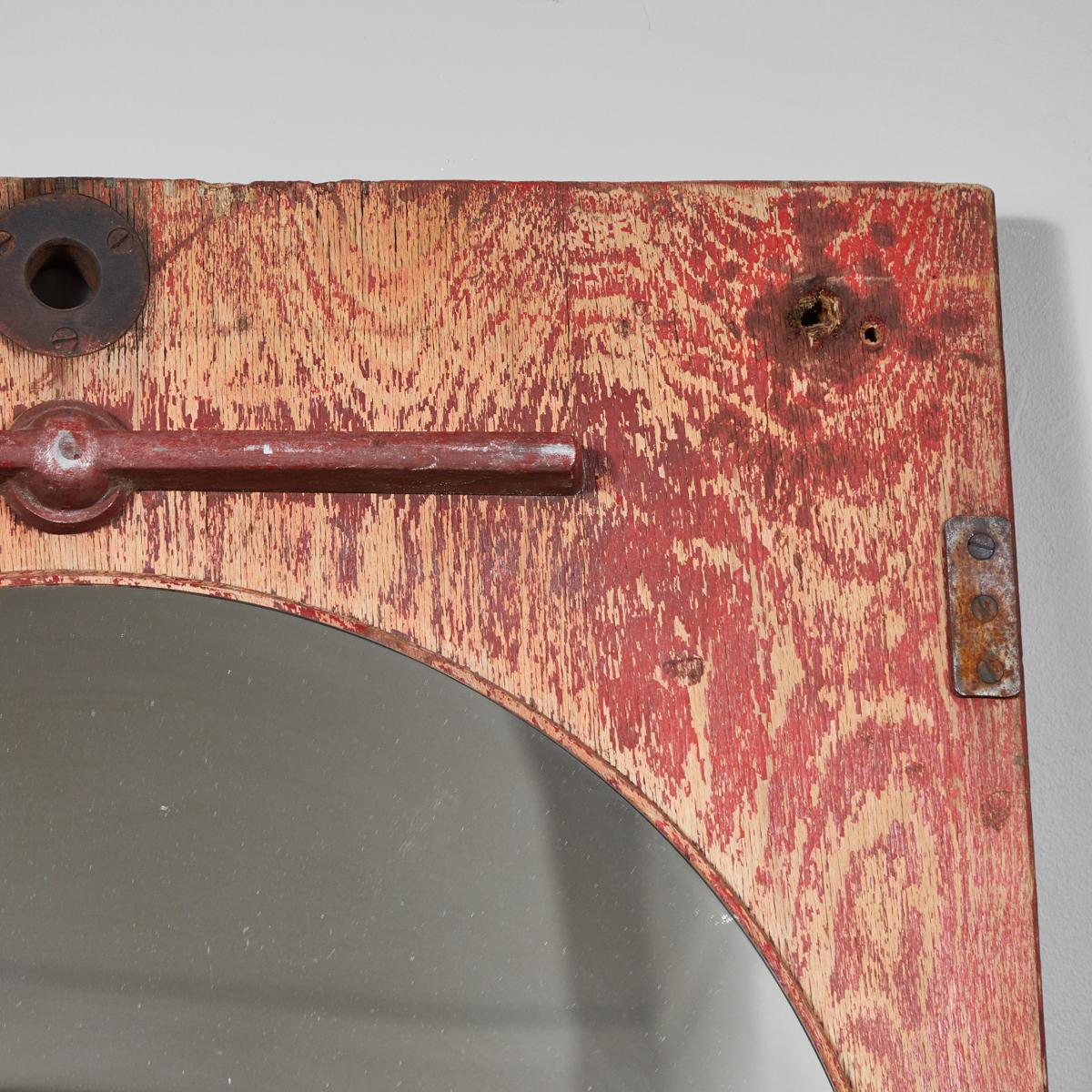 Circular mirror in a worn red industrial rectangular element.Originating in France dating to 1890.