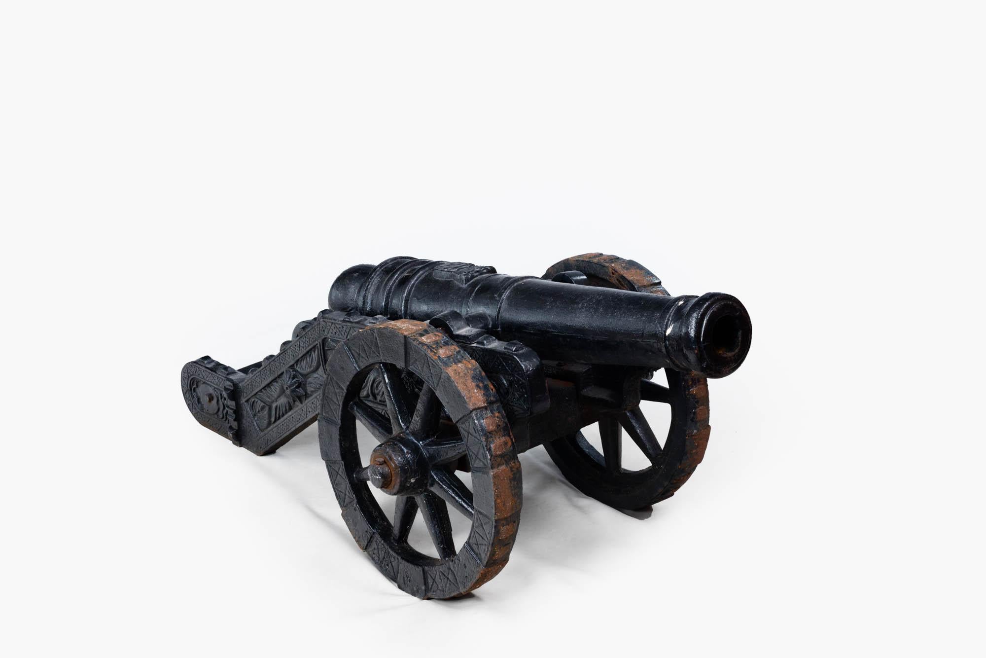 Late 19th century pair of decorative cast iron signaling cannons. Sitting on Cast trucks with embossed decoration having spoked cast wheels. The wheels have raised rectangular iron treads, and they are held to the axles by small metal pins.