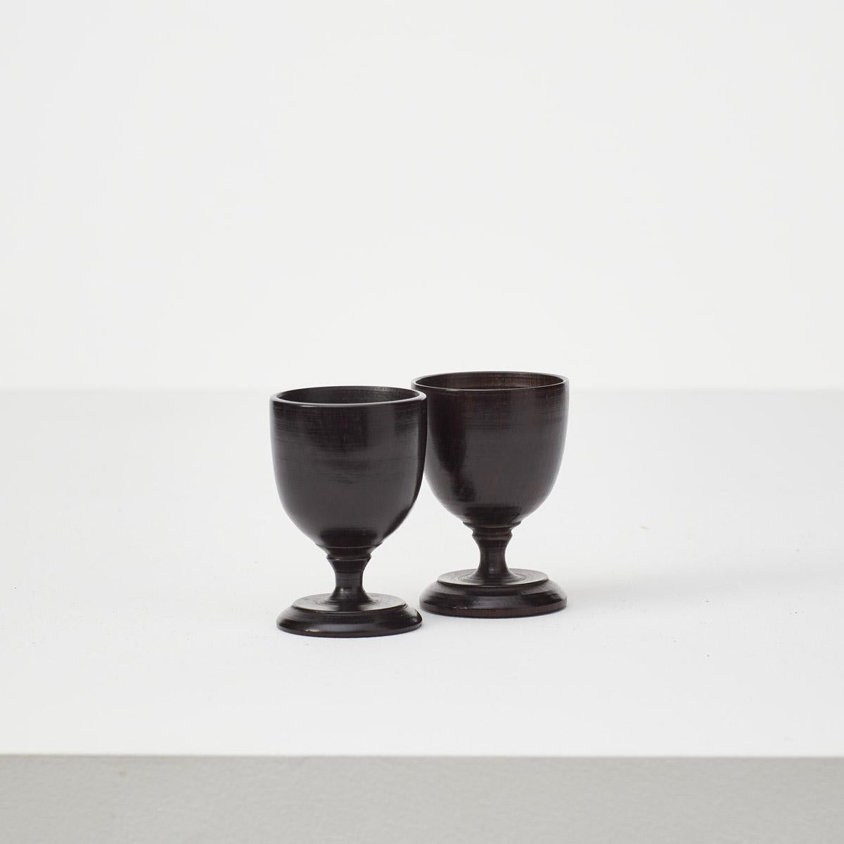Hand carved upon a lathe, this pair of ebonised wooden egg cups are small and perfectly formed. The hand carving creates a slight variation in the size of the cups. In great vintage condition, with some light marks to the surface.
