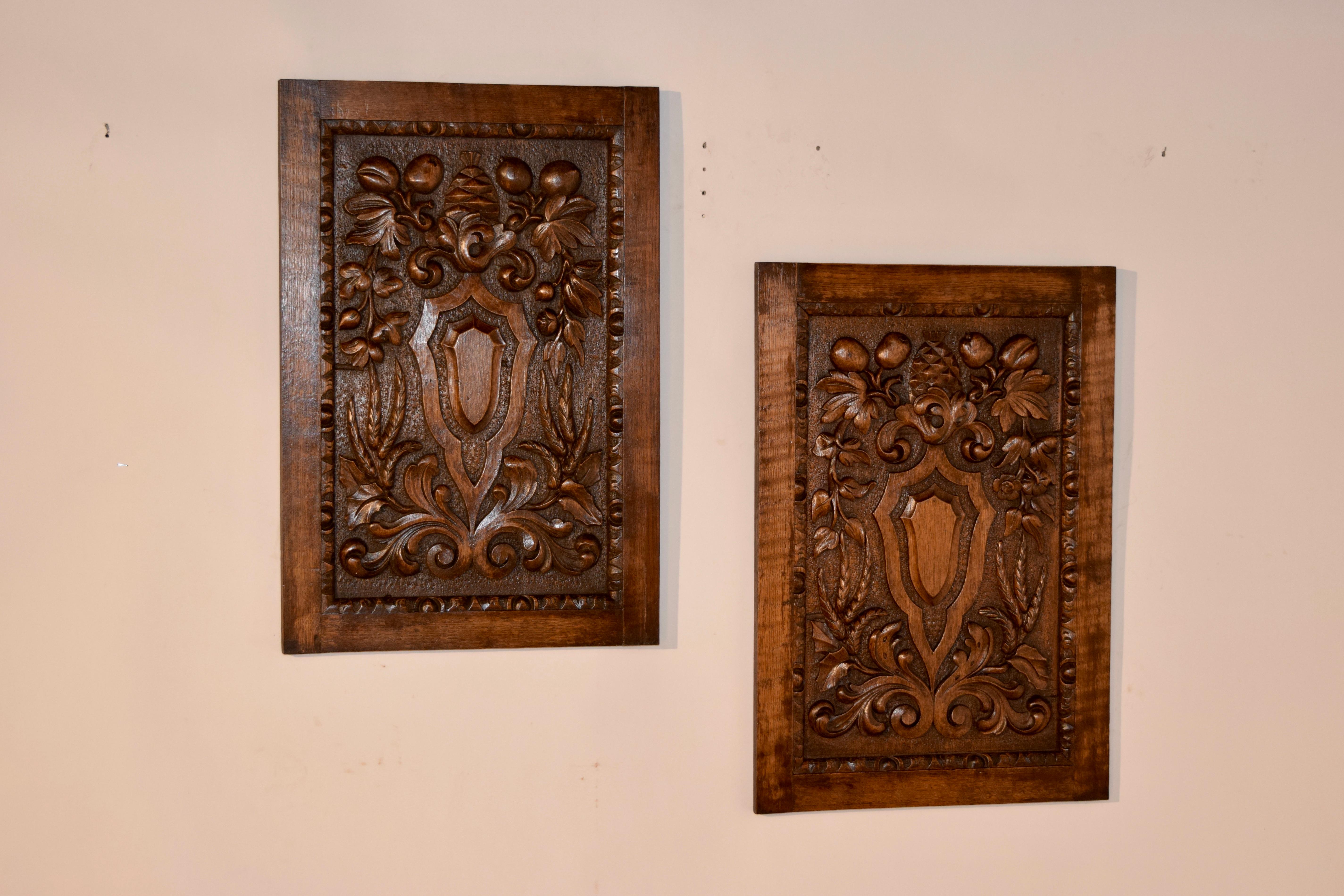 Pair of late 19th century carved oak panels from France with hand-carved shields in the center surrounded by carved fruit and floral. Lovely forms.