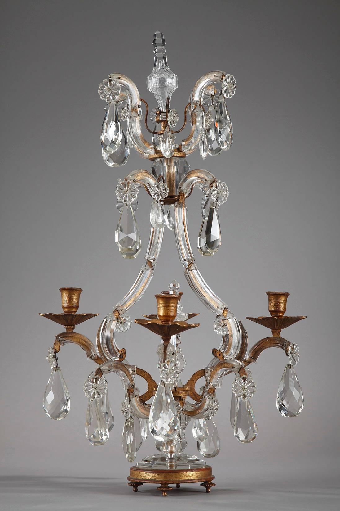 Pair of gilt bronze and crystal candelabra with four curved arms. The arms are sheathed in crystal and are decorated with teardrop and rosette crystal pendants. The central barrel is topped with a decorative dagger, and the ensemble rests on a