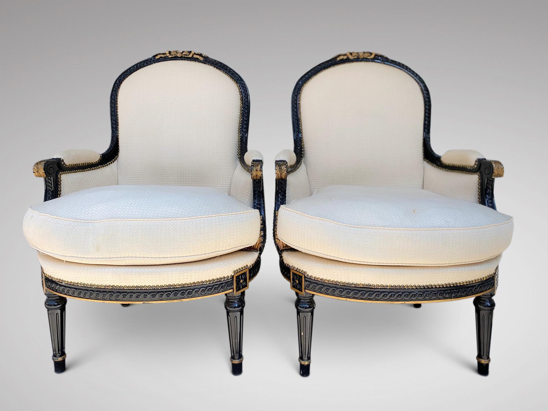 A pair of late 19th century French Louis XVI bergères. Ebonised and gilded finish to the wood, upholstered in a white and gild fabric with feather-stuffed seat cushion, sides and back in a blue purple fabric. Nice proportions and very comfortable in