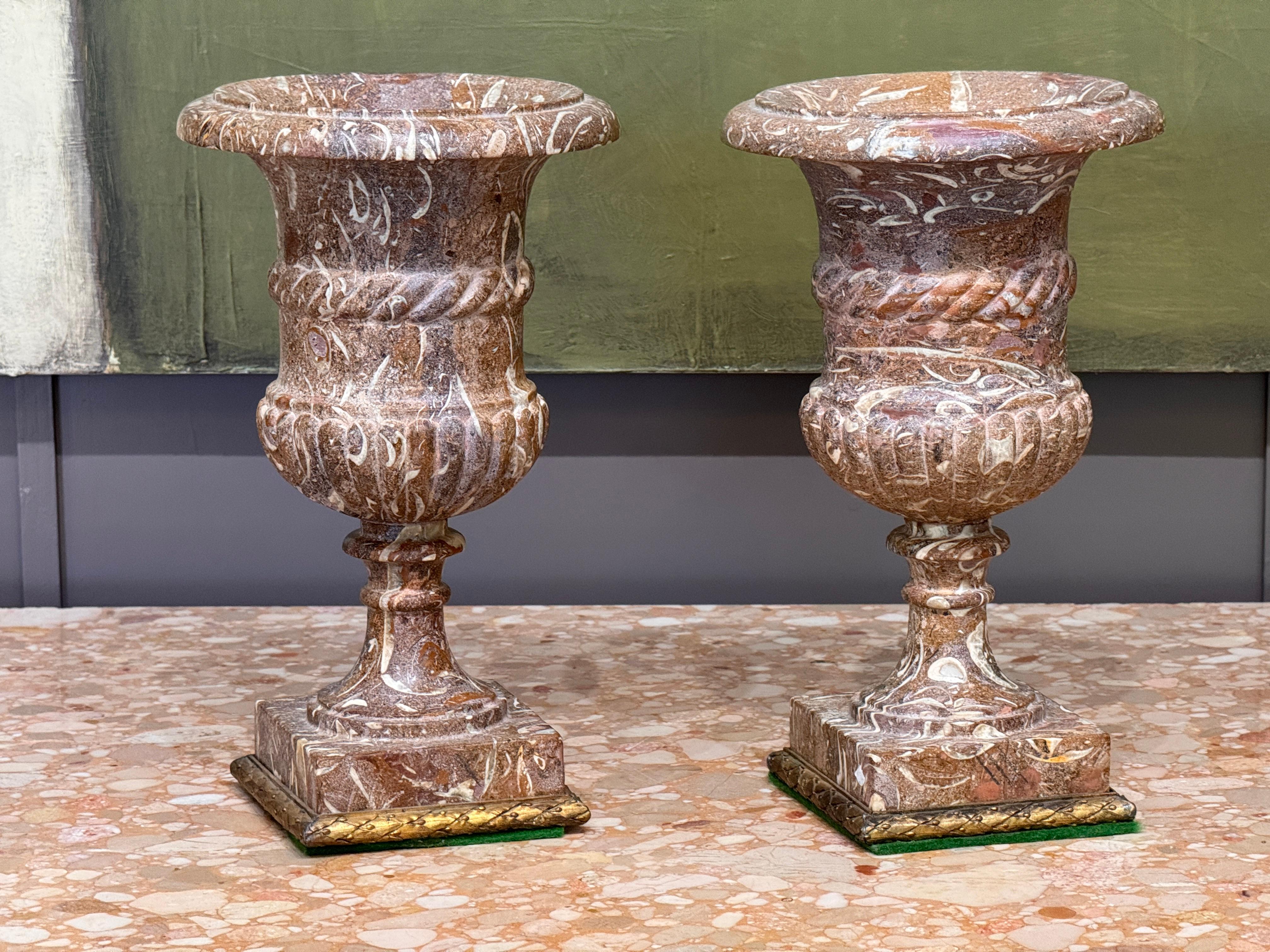 Pareja de urnas de estilo clásico de finales del siglo XIX, finamente talladas en mármol ricamente veteado con decorativas bases cuadradas montadas en ormolu. Los balaustres presentan detalles estriados y acanalados, con una ornamentación nítida y