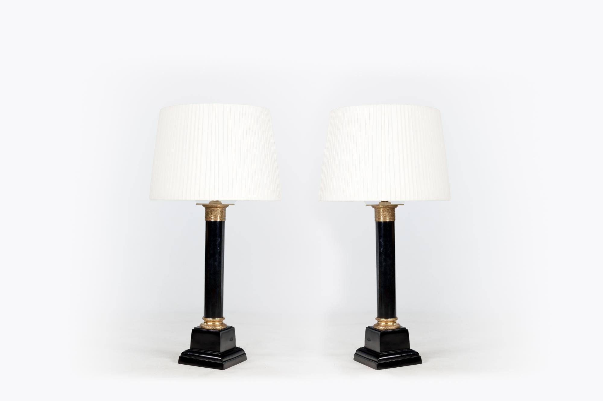 Late 19th century pair of metal column table lamps with ormolu mounted capitals on stepped square bases with a black gloss finish.