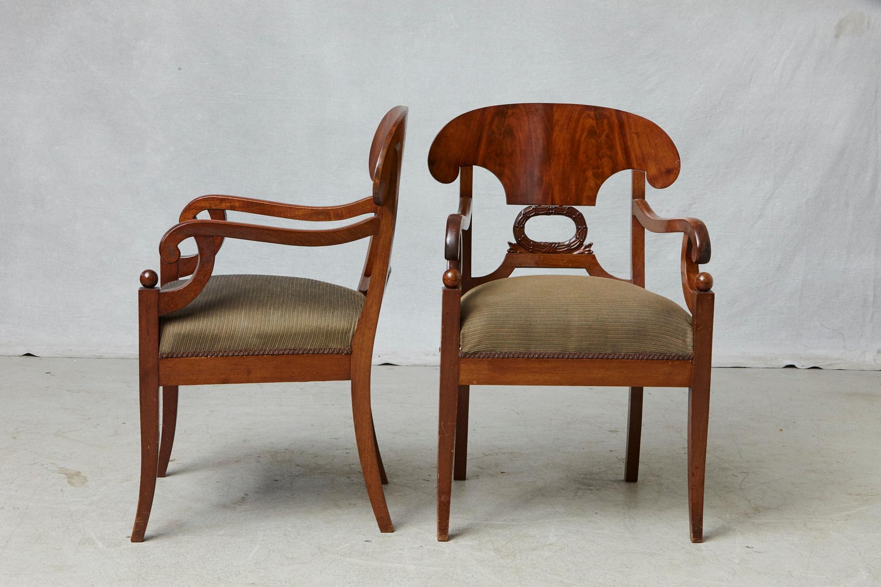 Pair of late 19th century Swedish Biedermeier or Karl Johan style birch wood armchairs with curved upper back over a wreath decor, scroll over arms and sabre legs with ball shaped finials, 
circa 1880-1900.
The chairs have a few smaller scratches