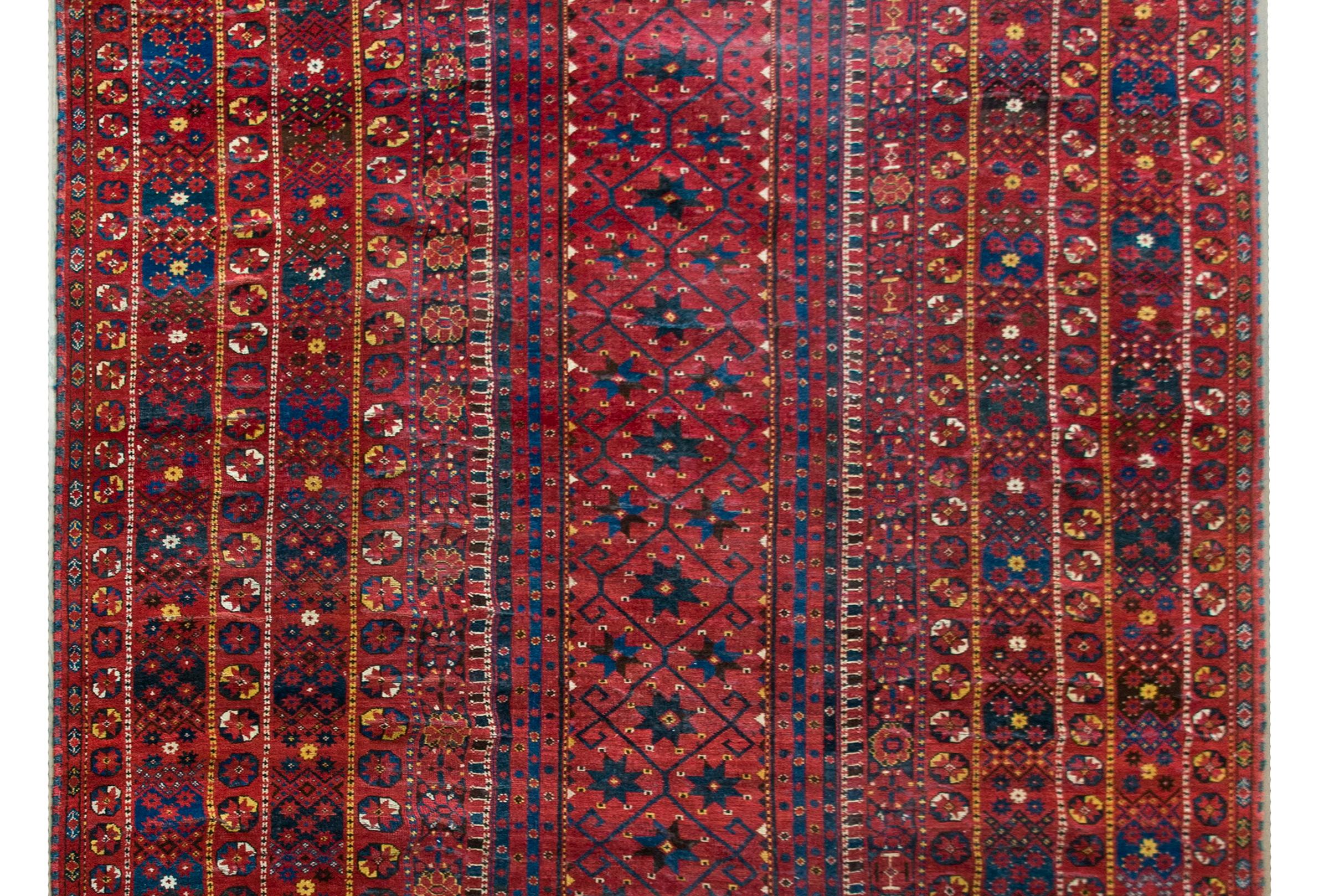 A striking and rare late 19th century Persian Afghani Bashir rug with a narrow central field of stylized flowers with a scrolling vines and surrounded by an unusually wide border composed of multiple different petite stylized flowers, and all woven