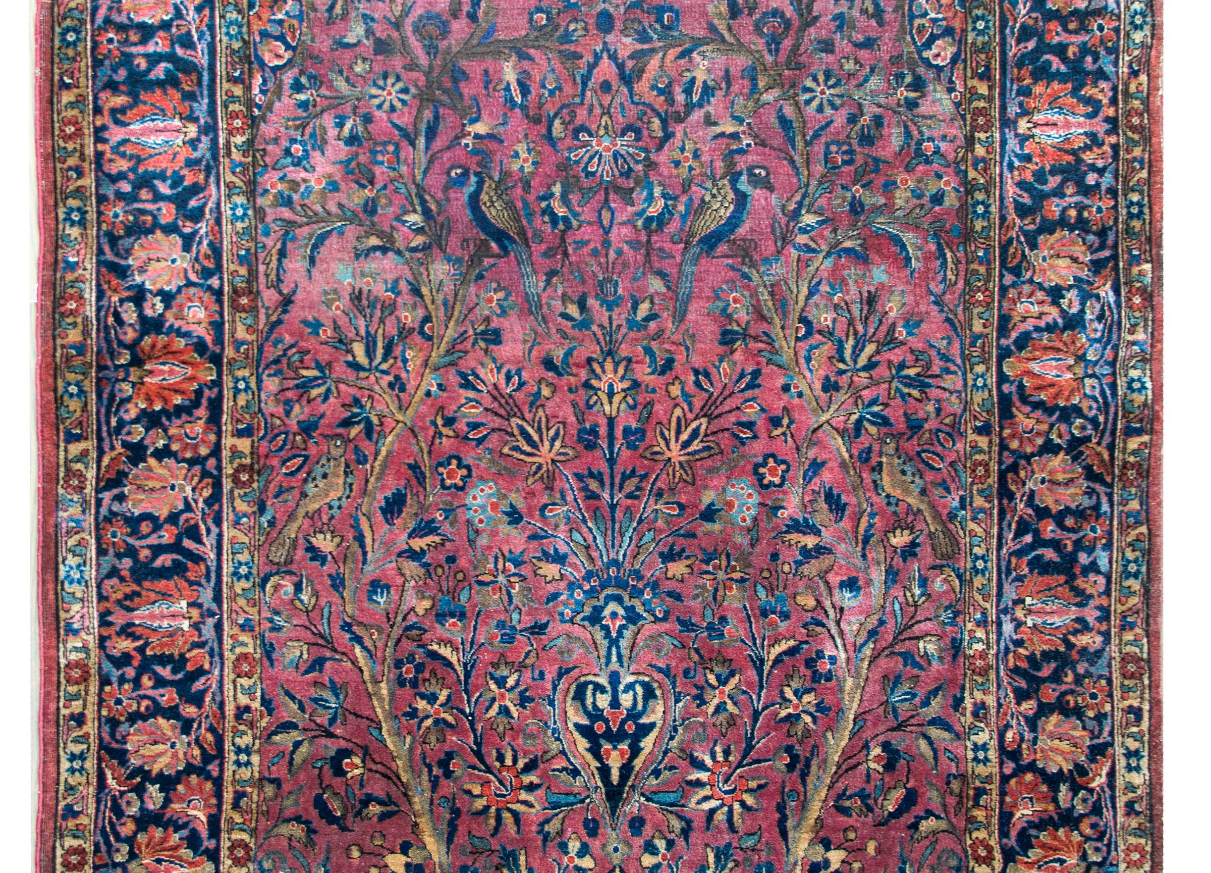 A stunning late 19th century Persian Kashan rug with an expertly woven double tree-of-life pattern containing two trees, mirror images of each other, full of flowering branches and myriad birds, both flanking a central vase potted with even more