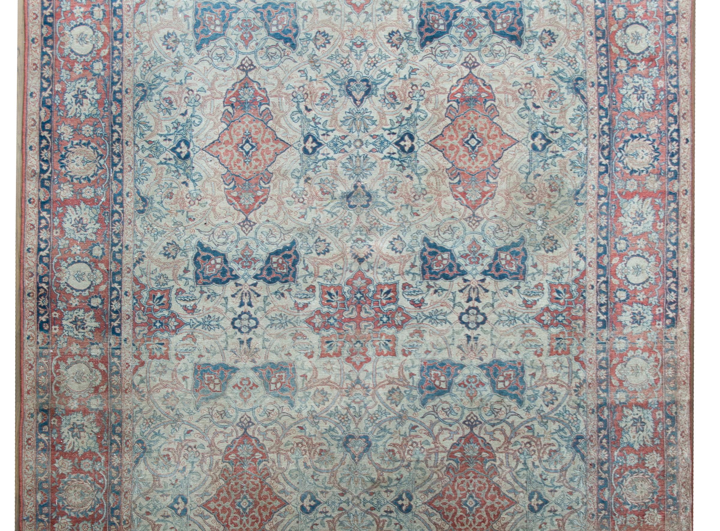 A stunning late 19th century Persian Isfahan rug with a large mirrored trellis pattern woven with myriad scrolling vines and stylized flowers, on an abrash ground that fades at one end.  The border is exceptional with even more large-scale stylized