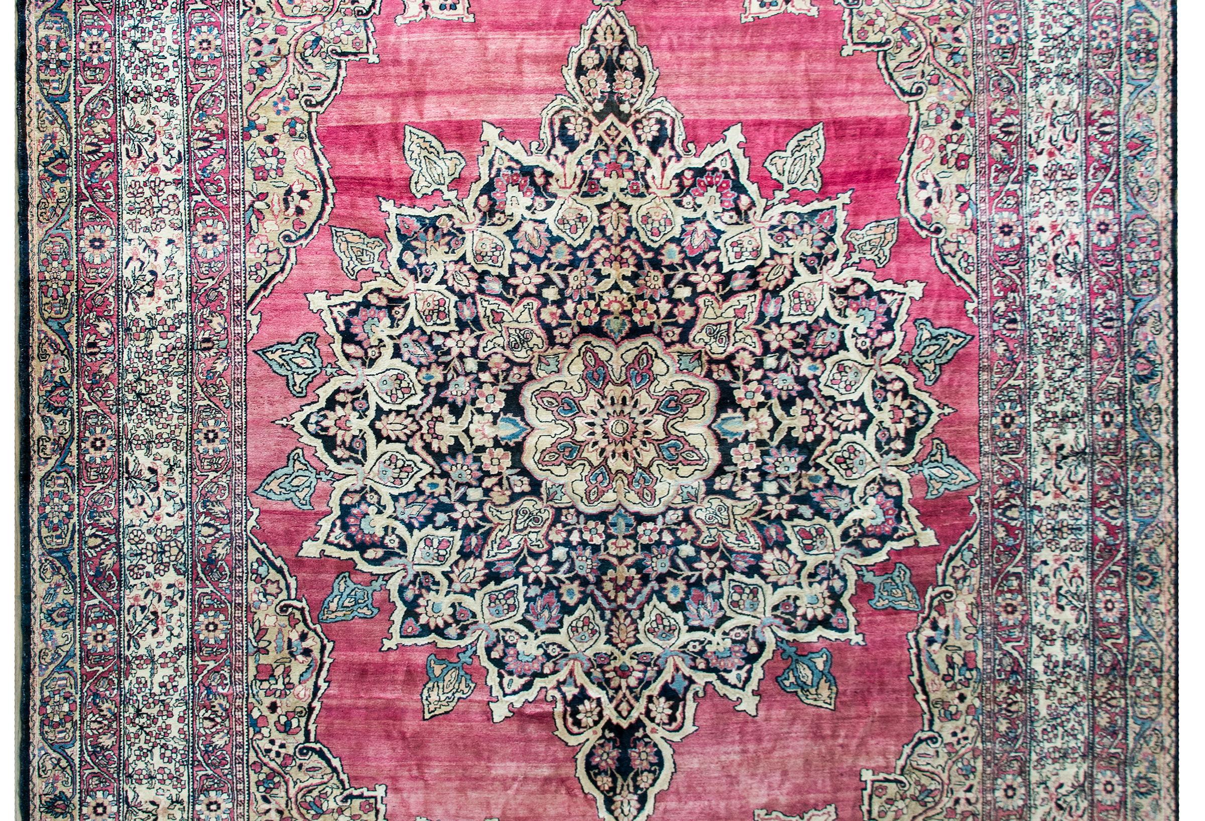A stunning late 19th century Persian Lavar Kirman rug with the most wonderful central floral medallion woven in traditional Kirman colors of light and dark indigo, pink, and cream, and set against an incredible abrash cranberry background, and all