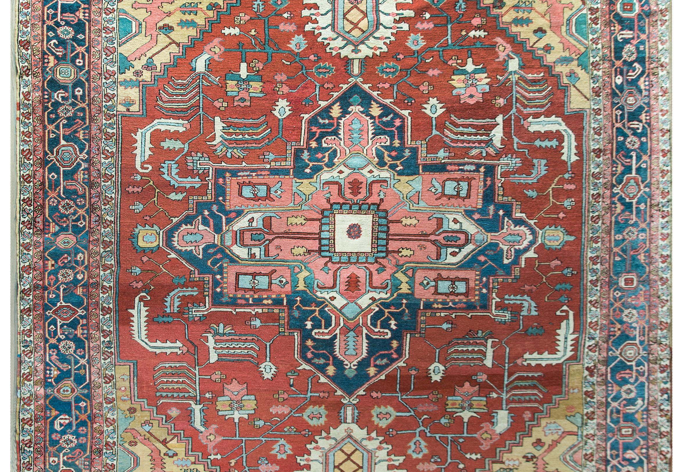 A remarkable late 19th century Persian Serapi rug with the a fabulous large central floral medallion living among a field with myriad stylized scrolling vines and flowers and woven in pinks, whites, golds, greens, and indigos, and all set against an