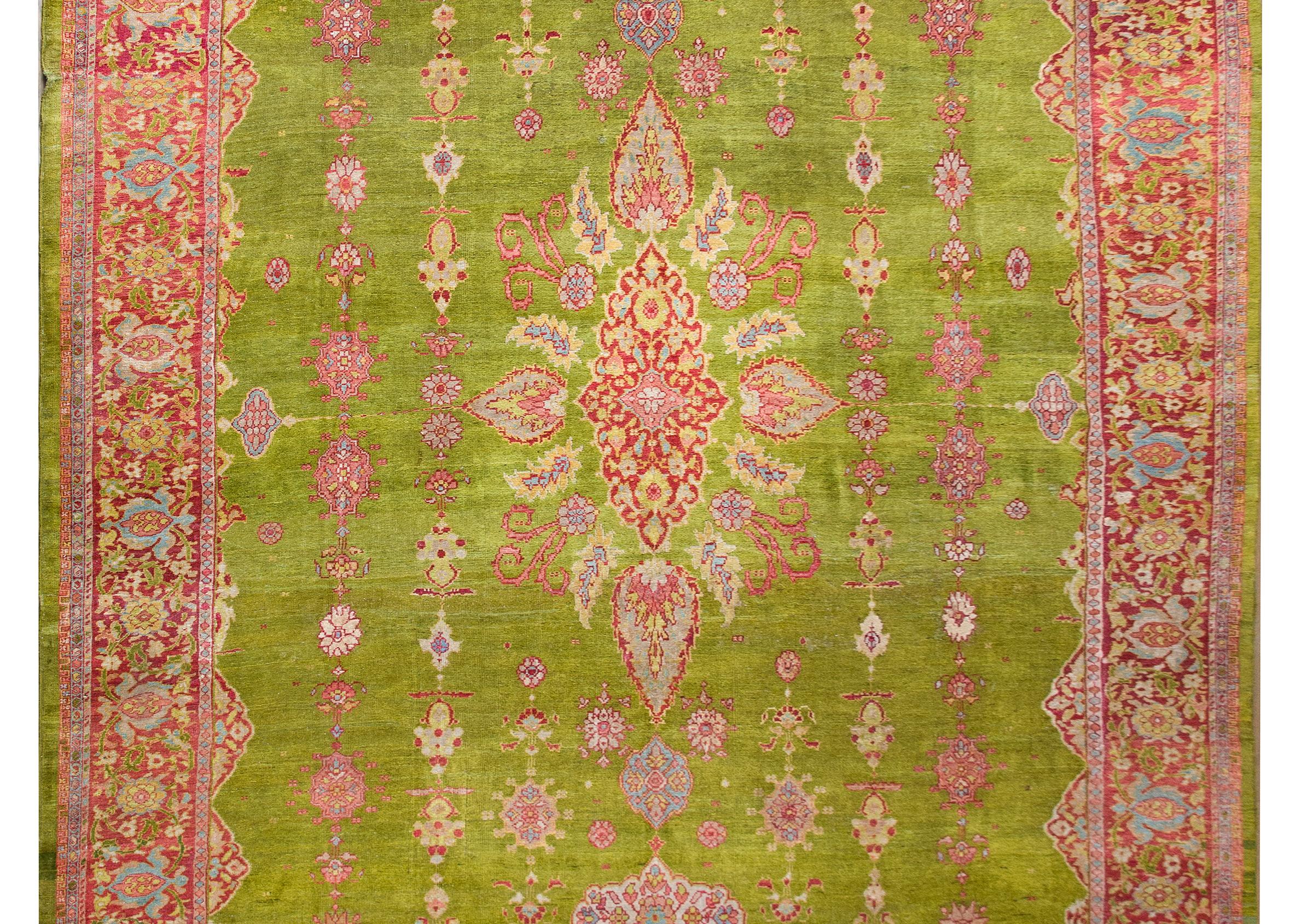 A stunning and rare late 19th century Persian Sultanabad rug with the most wonderful central floral medallion living amidst a field of more stylized flowers all woven in brilliant cranberry, light indigo, pink, and gold, and set against a rare