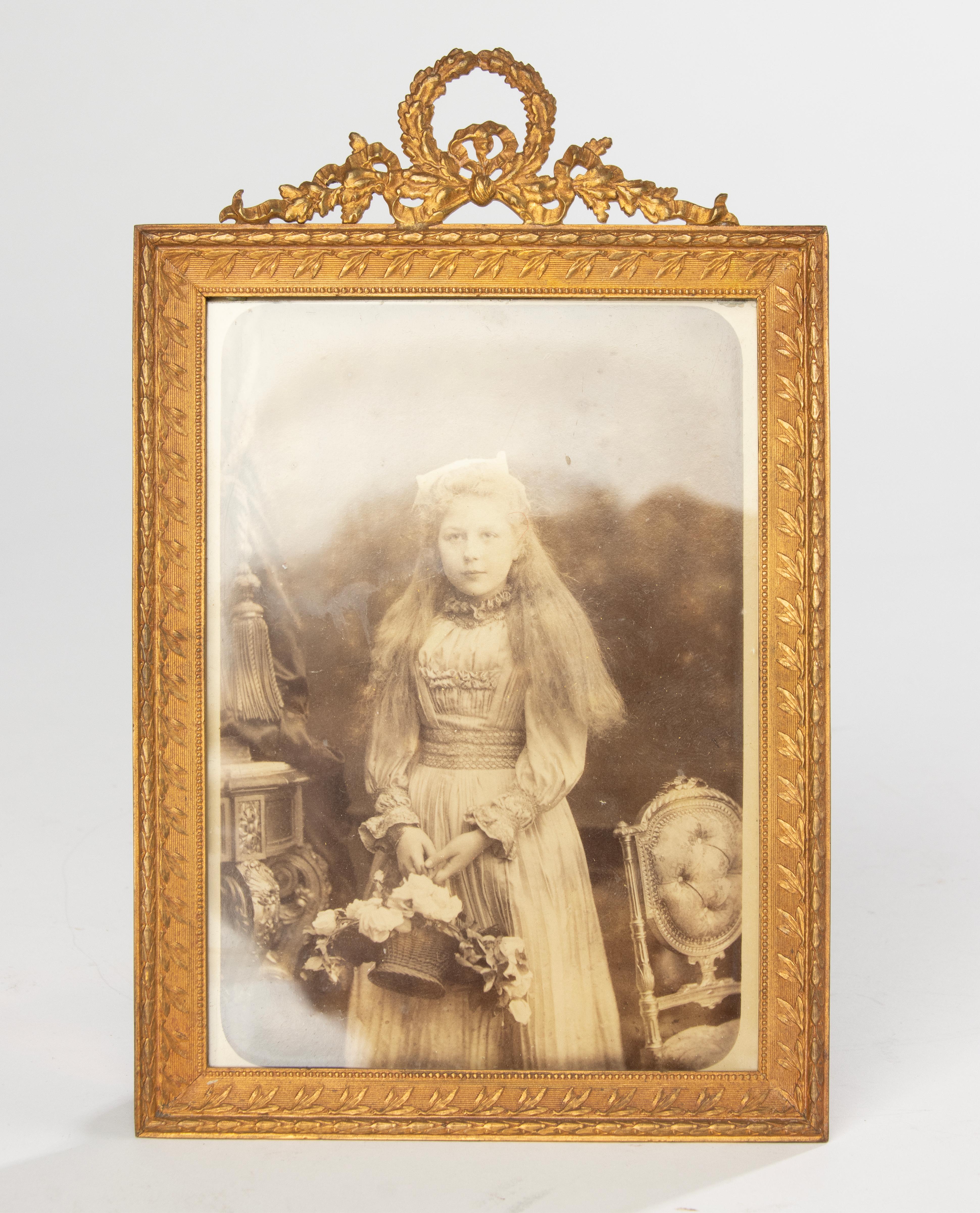 Elegant and refined 19th century French photo frame in the Louis XVI style. Crafted in bronze with exquisite ormolu (gilt bronze) finish, the frame features finely cast details including a delicate ribbon bow crest and laurel leaf garland —