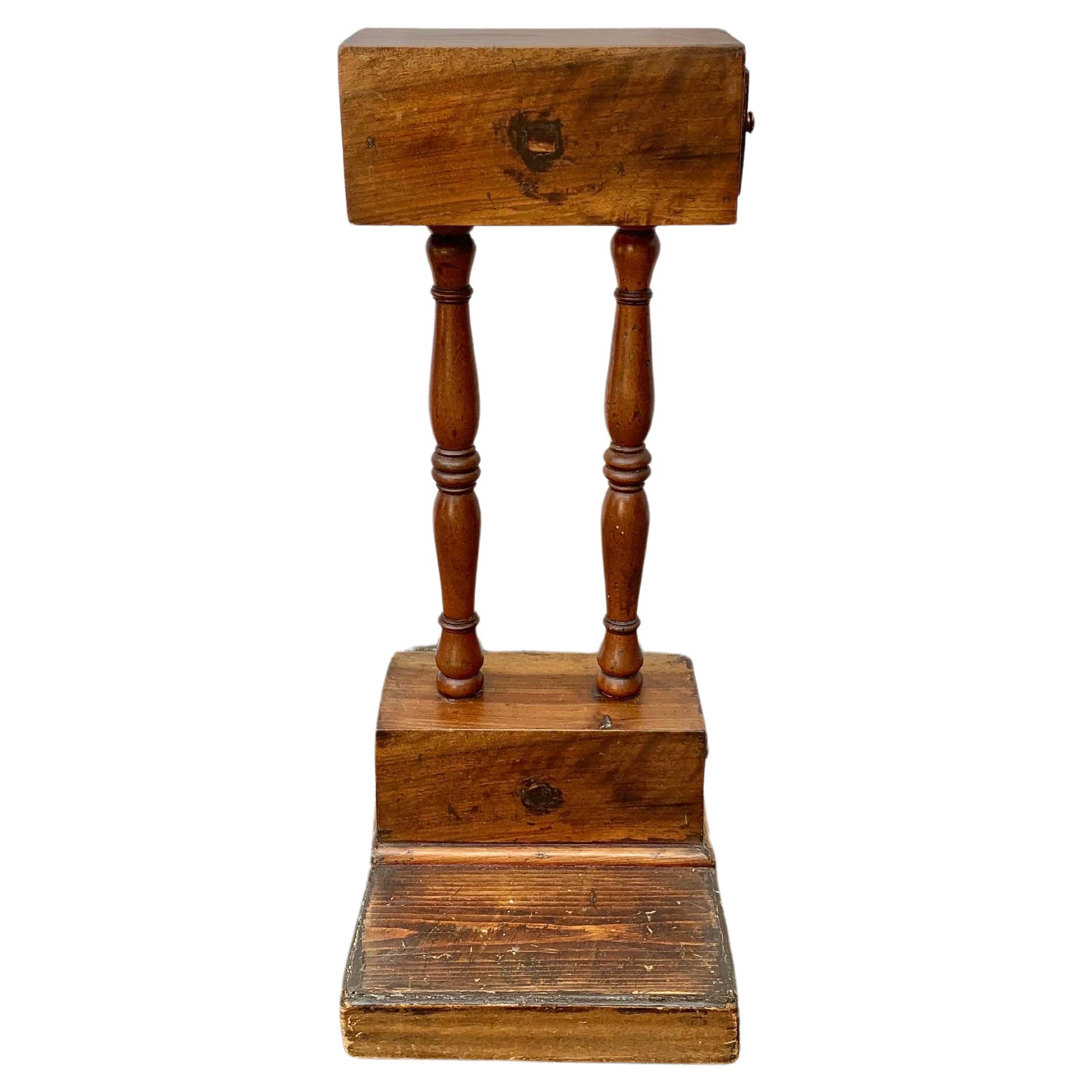 This one of a kind Late 19th Century Tobacco Stand was handcrafted in the 1800's from Walnut and Pine. The piece features a rectangular box style top consisting of a small drawer that is supported by hand turned supports adjoined to another