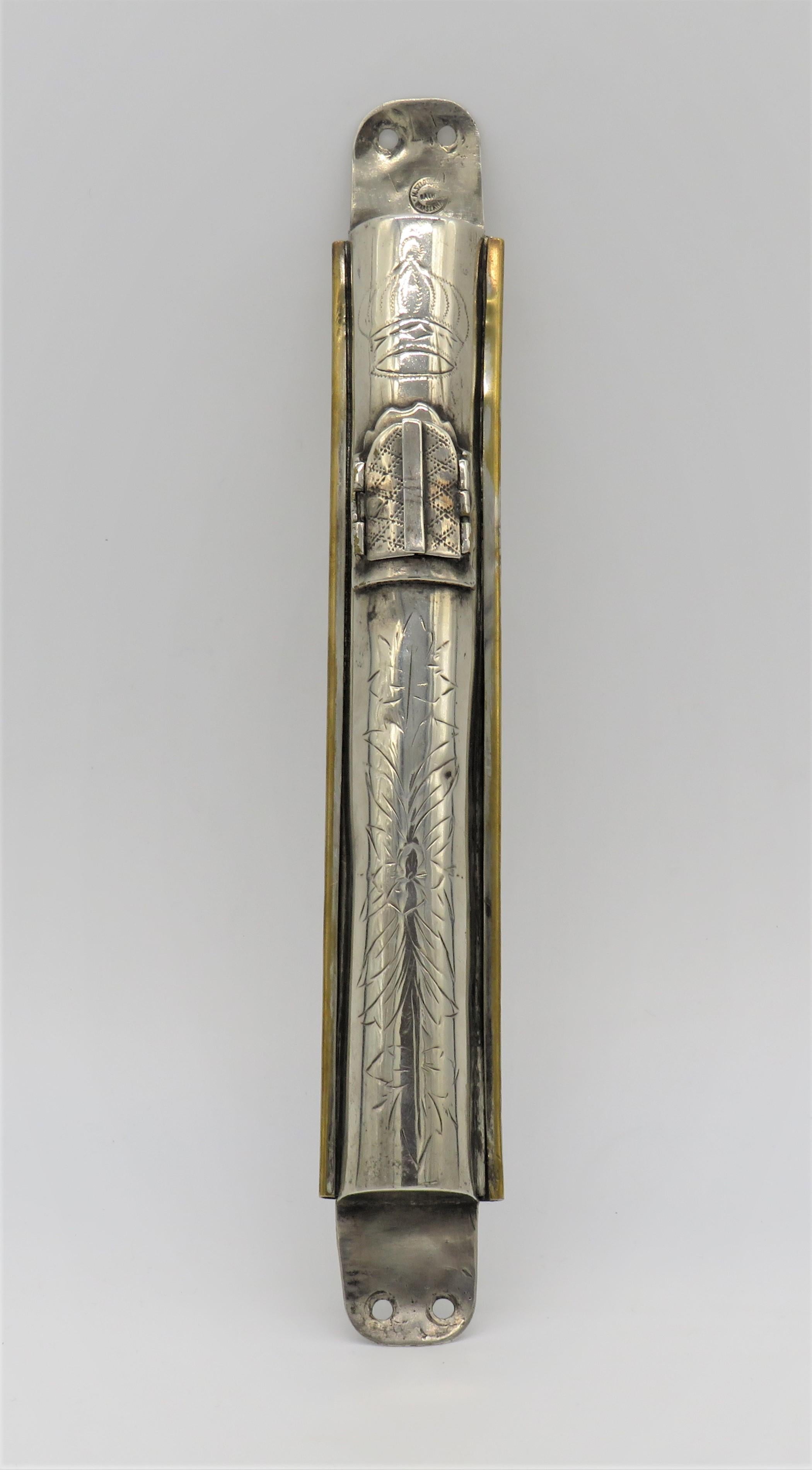 Silvered brass Mezuzah case by M. Szlossberg, Warsaw, Poland, circa 1890.
Hand-engraved with crown and with floral design.
The mezuzah has a small window with two doors, allowing to see the parchment inside.
Stamped with maker's mark and with the