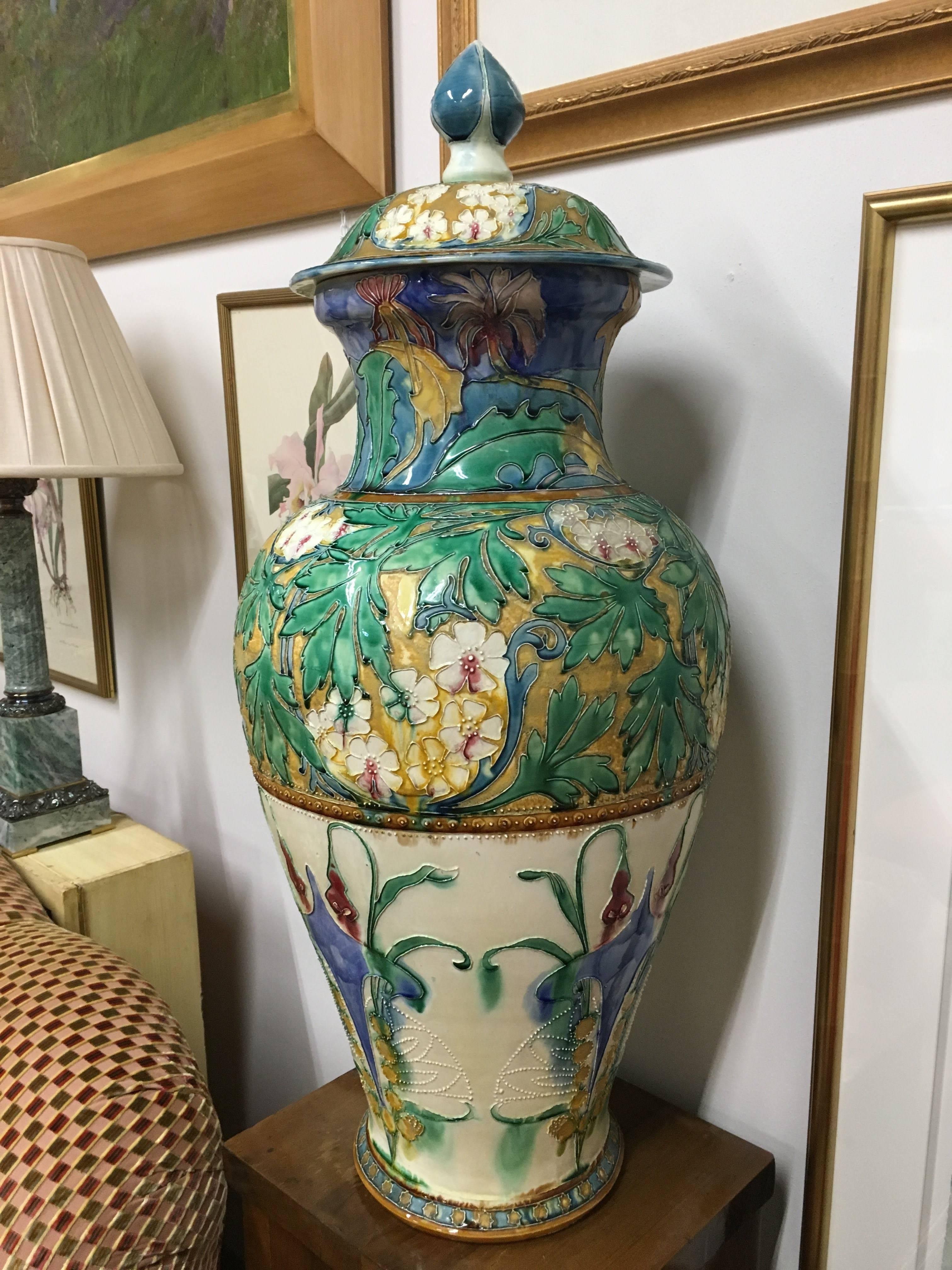 Oversized late 19th century Portuguese Palissy ware covered vase elaborately decorated in the Art Nouveau style featuring translucent applied enamel depictions of florals, twining greenery and fresh blooms in the highly-desired earthy muted jewel
